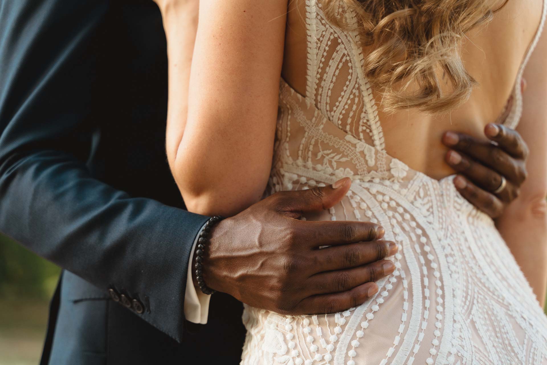 La mano dello sposo sulla schiena di pizzo della sposa