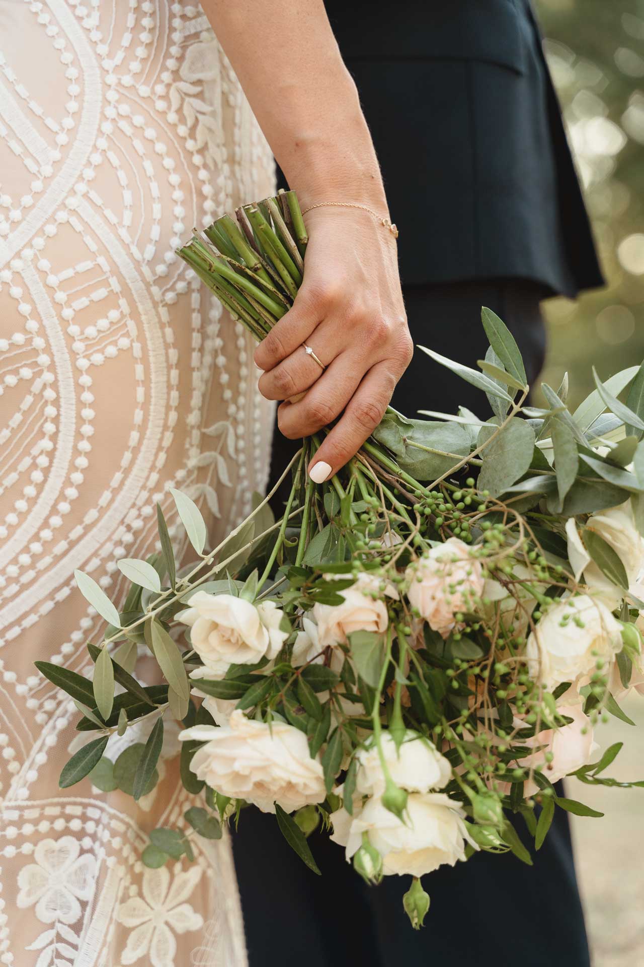 Il bouquet stretto nella mano della sposa, contro l'abito