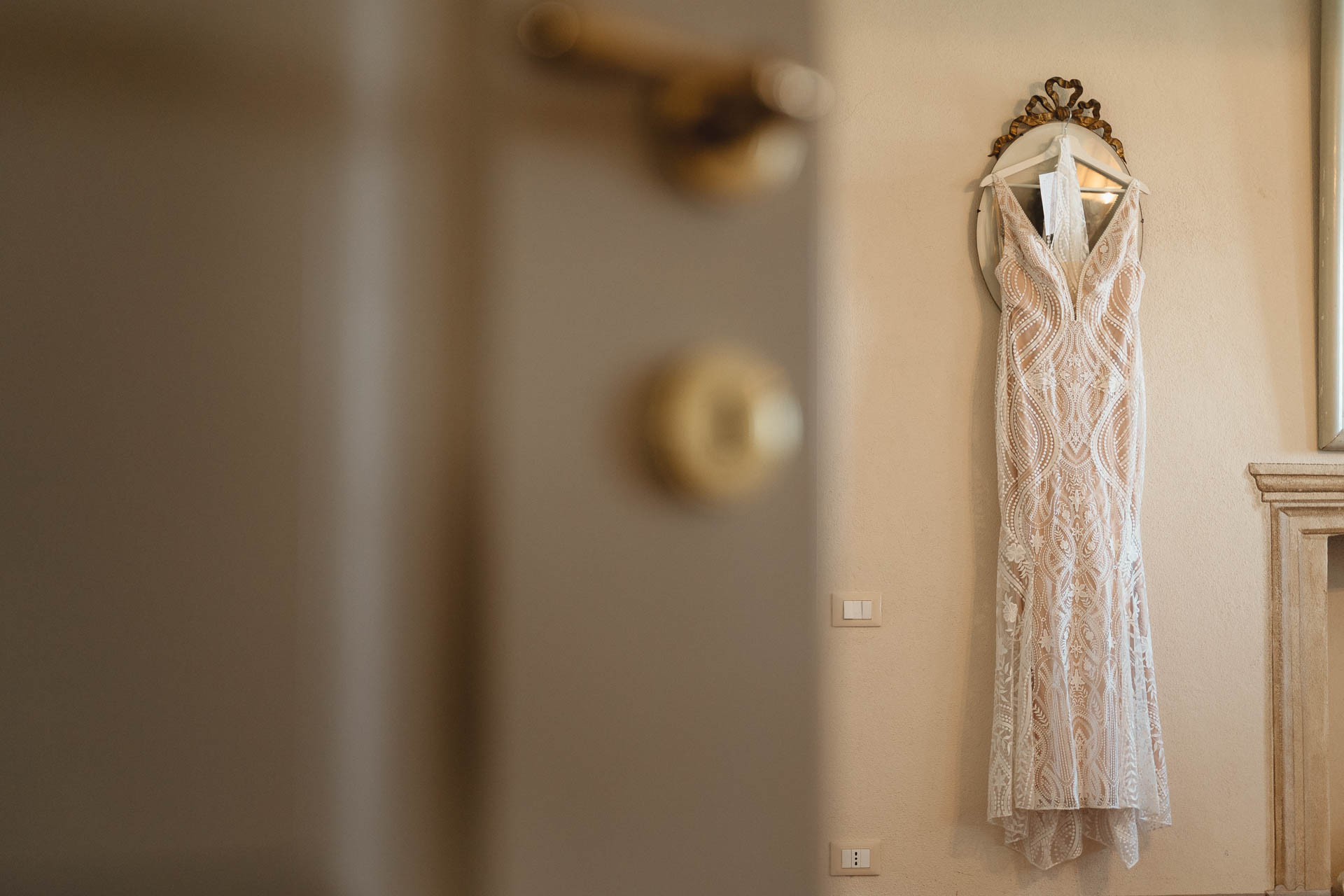 L'abito da sposa appeso, oltre la porta socchiusa