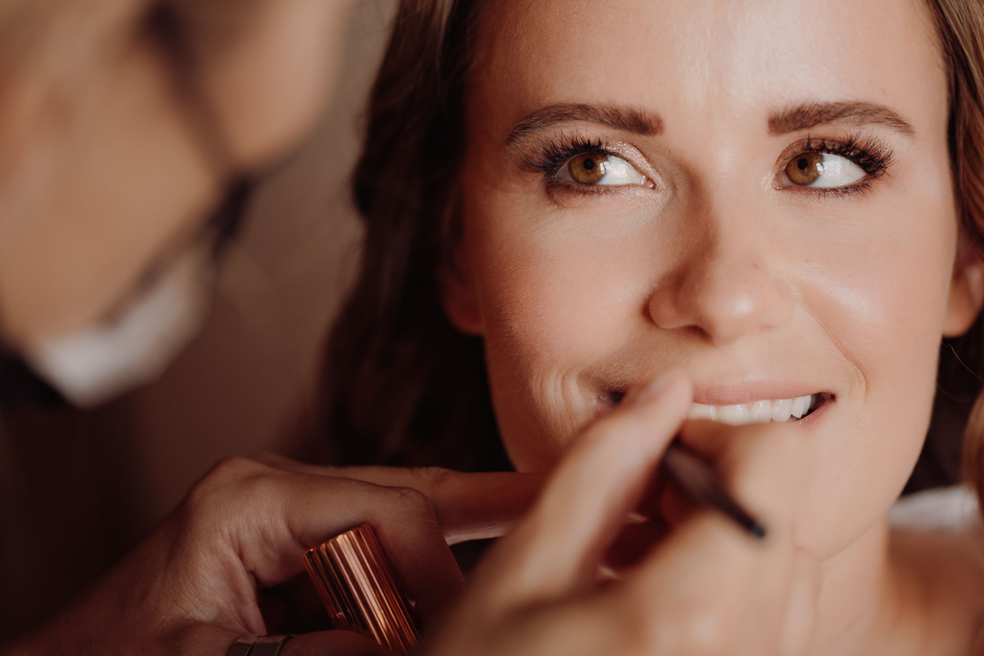 La sposa sorride mentre la truccano
