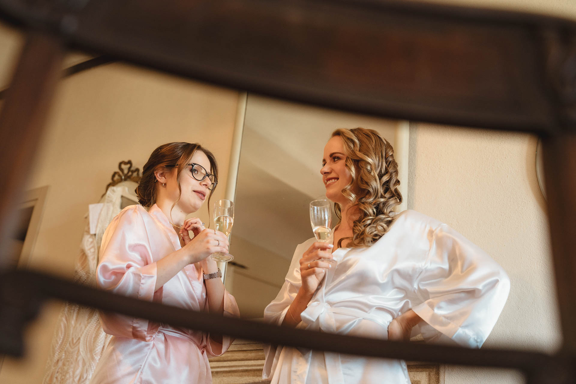 La sposa e un'amica con i calici, riflesse nello specchio