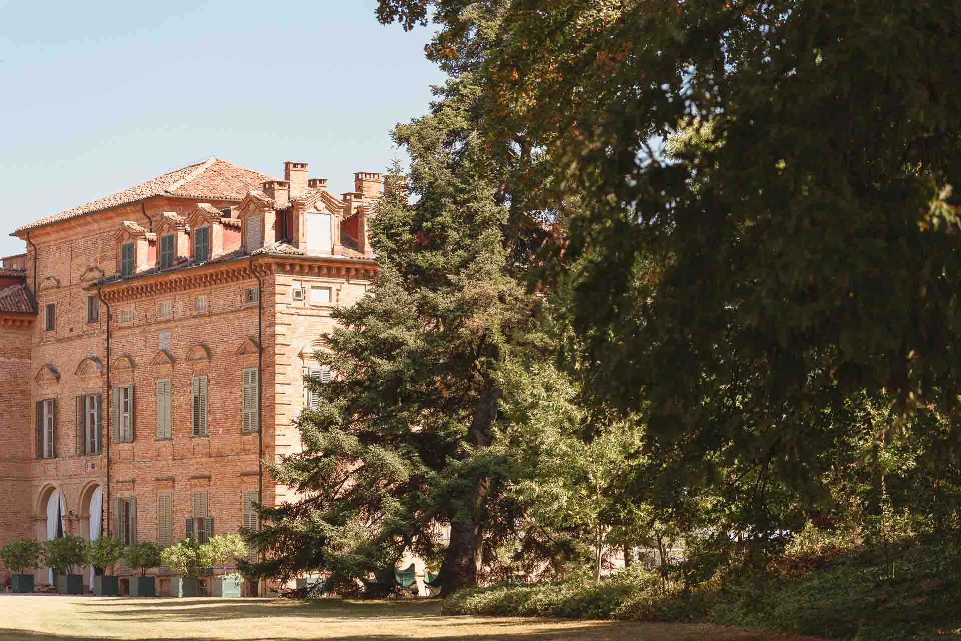 La facciata in mattoni del castello della Tenuta Marchesi Alfieri, tra gli alberi del parco