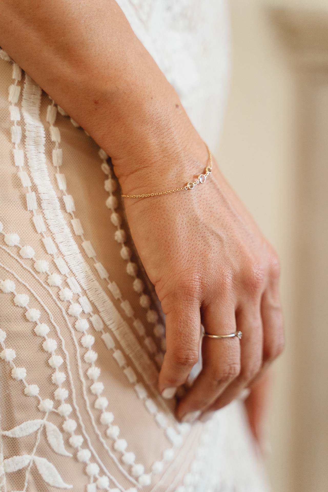 La mano della sposa con l'anello, sul ricamo dell'abito