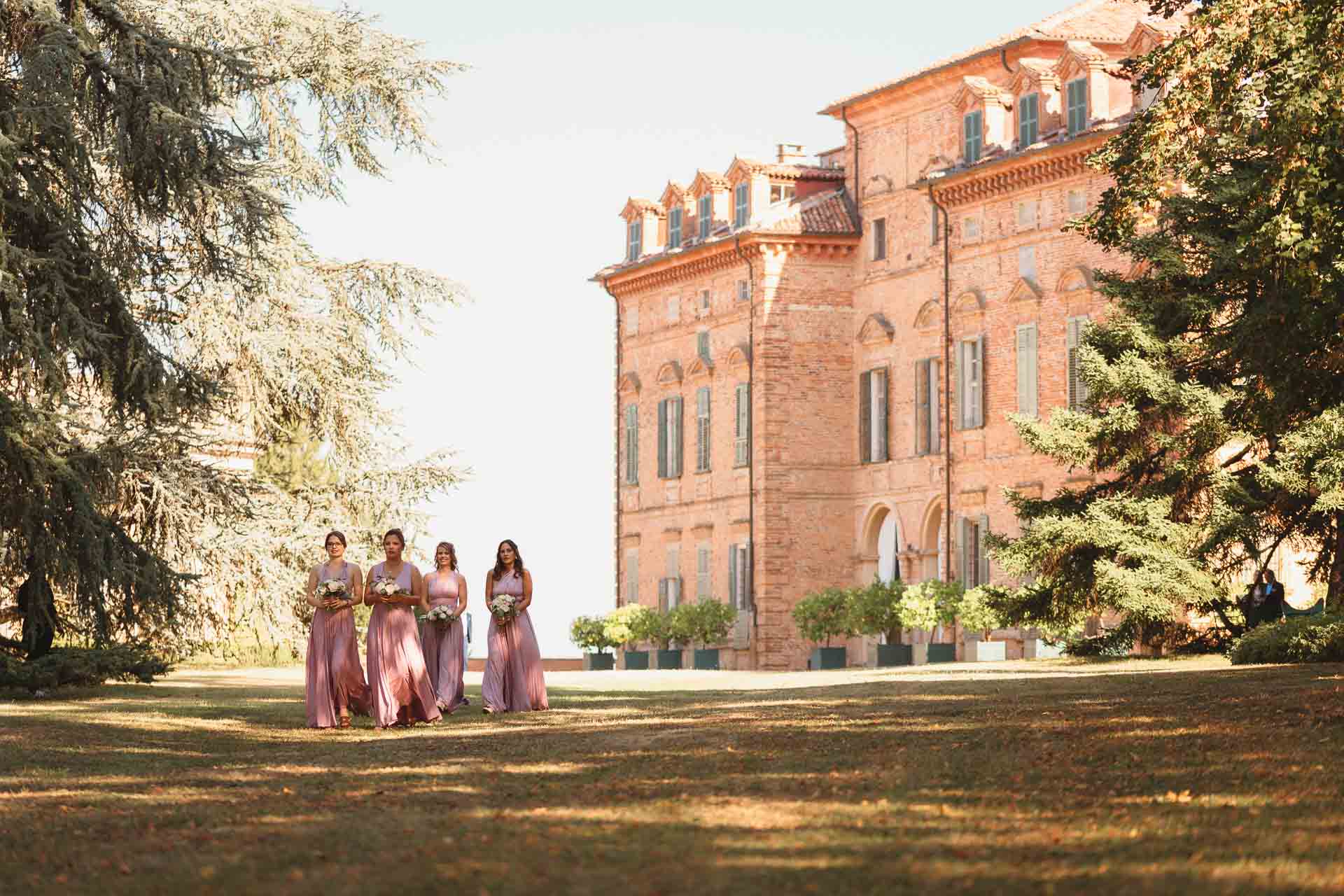 Le damigelle in rosa attraversano il prato davanti al castello