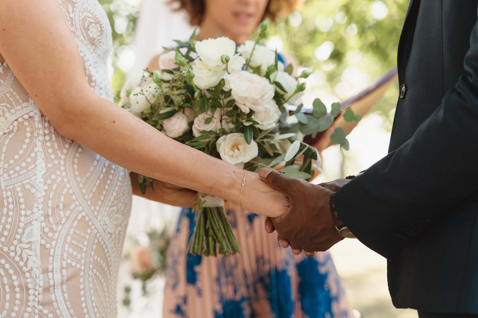 Le mani degli sposi strette, con il bouquet