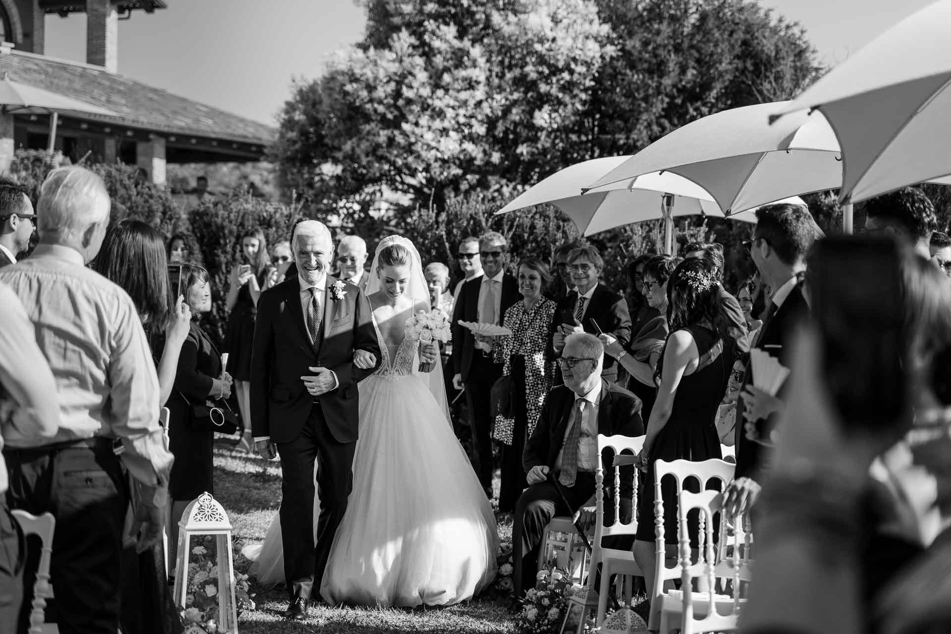In bianco e nero, il papà accompagna la sposa tra gli invitati