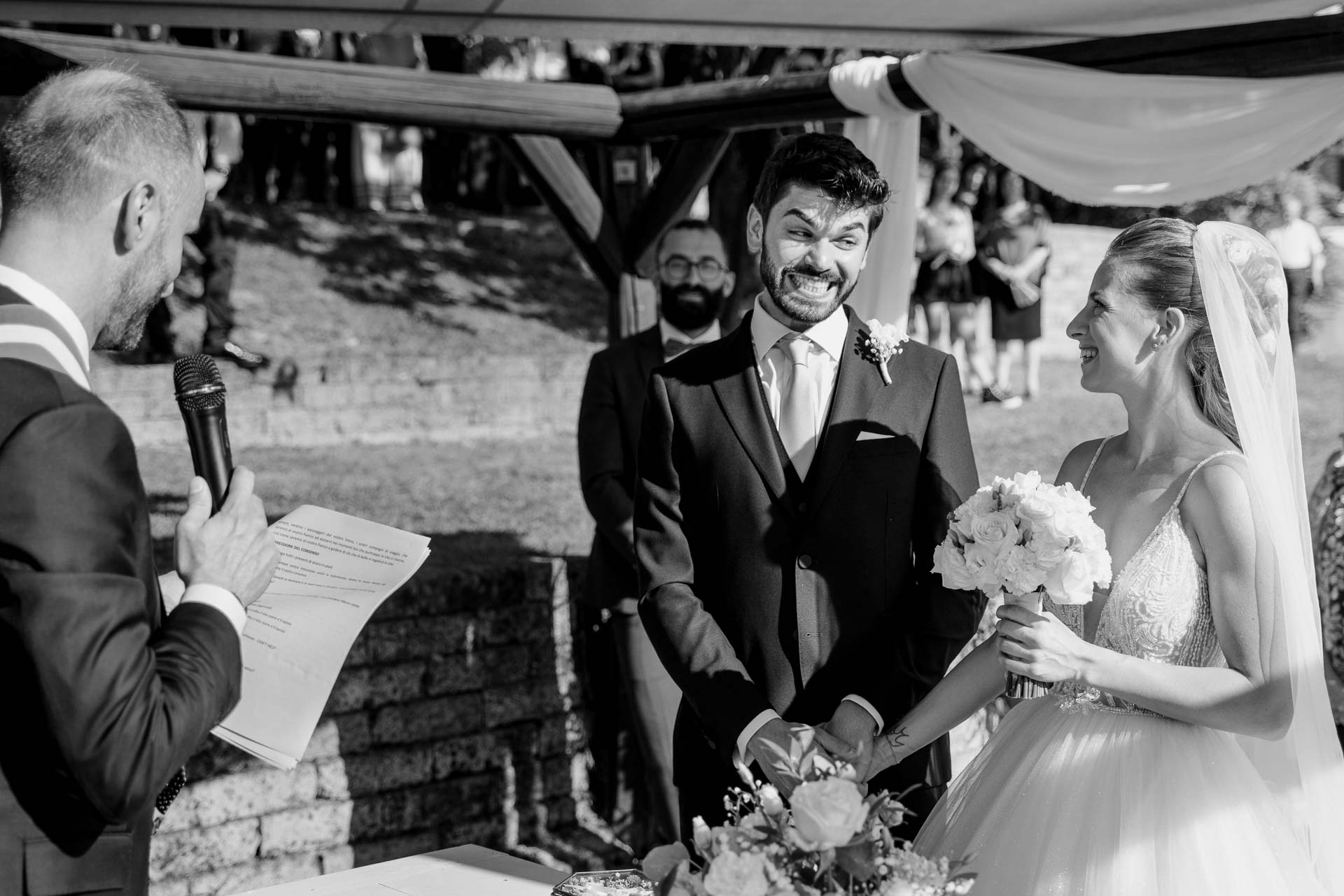 In bianco e nero, lo sposo ride mentre il celebrante legge
