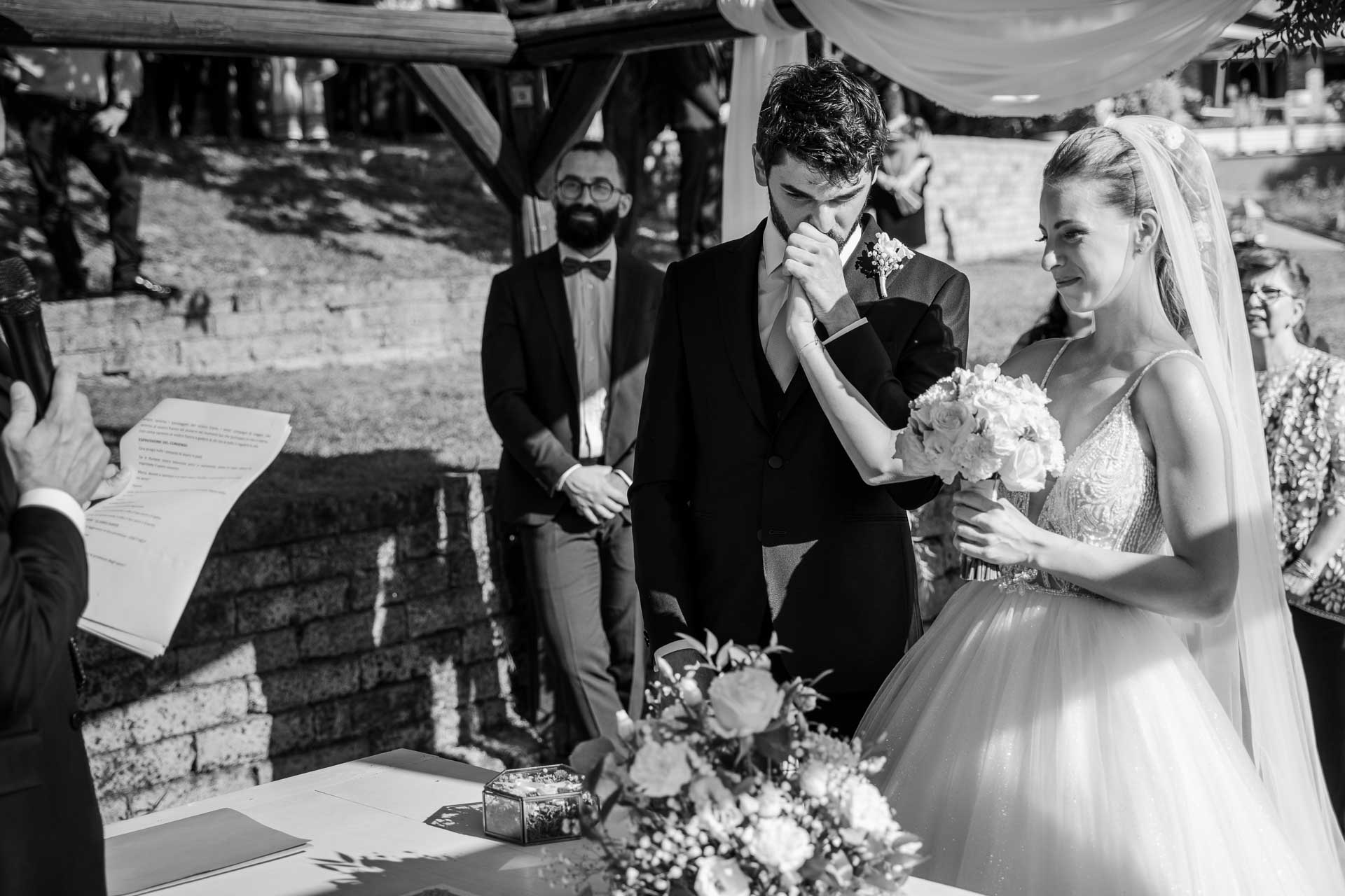 In bianco e nero, lo sposo si copre il viso, commosso, accanto alla sposa