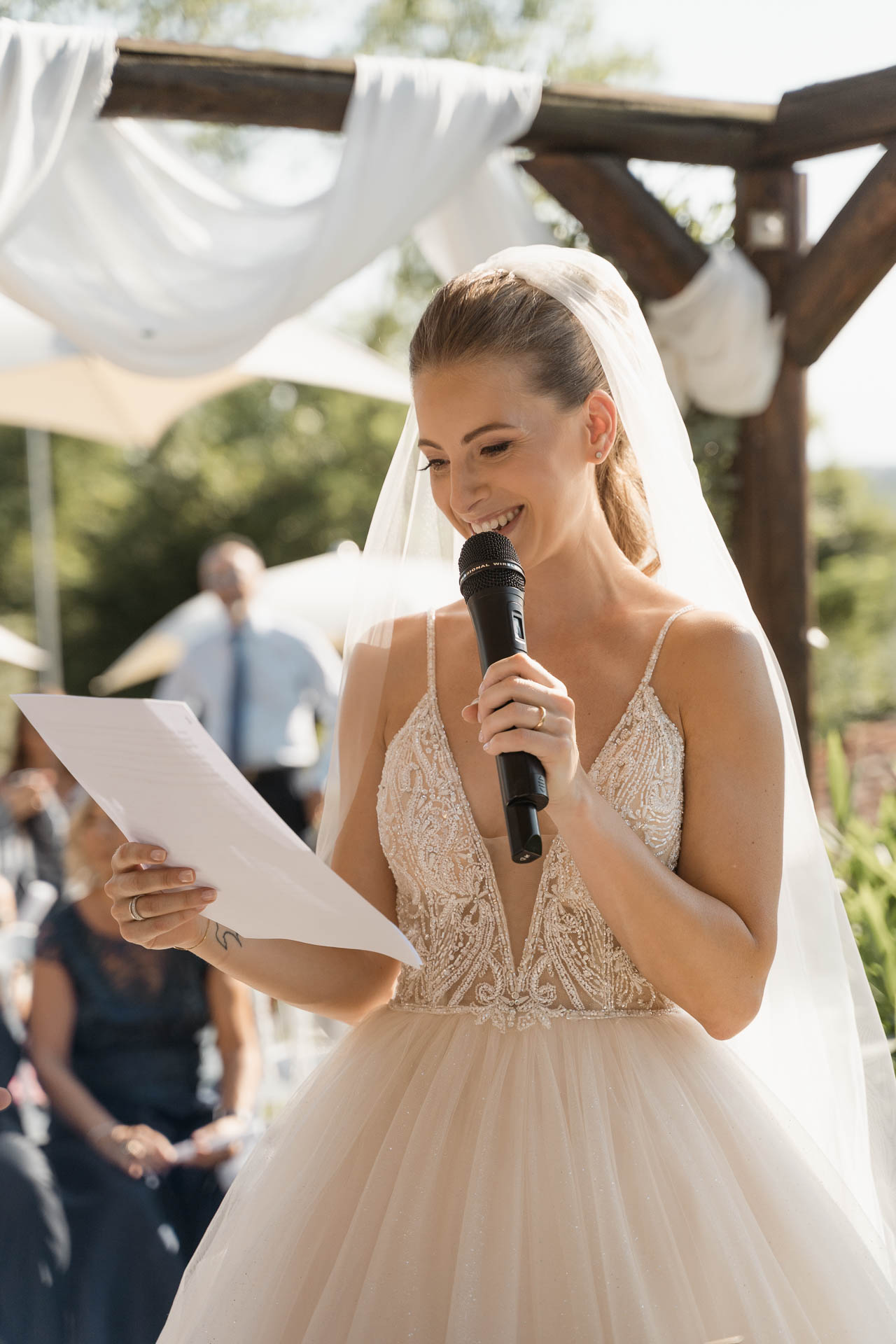 La sposa legge le promesse al microfono, sorridendo