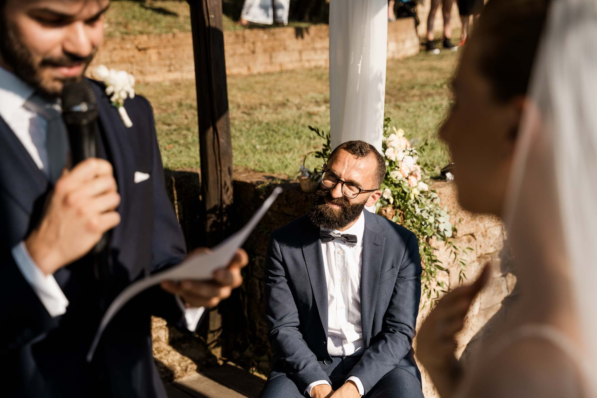 Lo sposo legge al microfono e l'amico in papillon lo ascolta