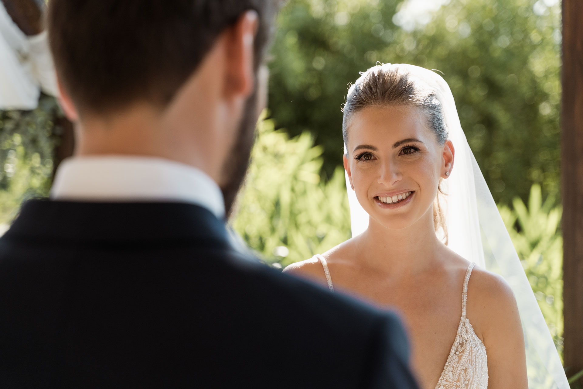 La sposa sorride allo sposo, vista oltre la sua spalla