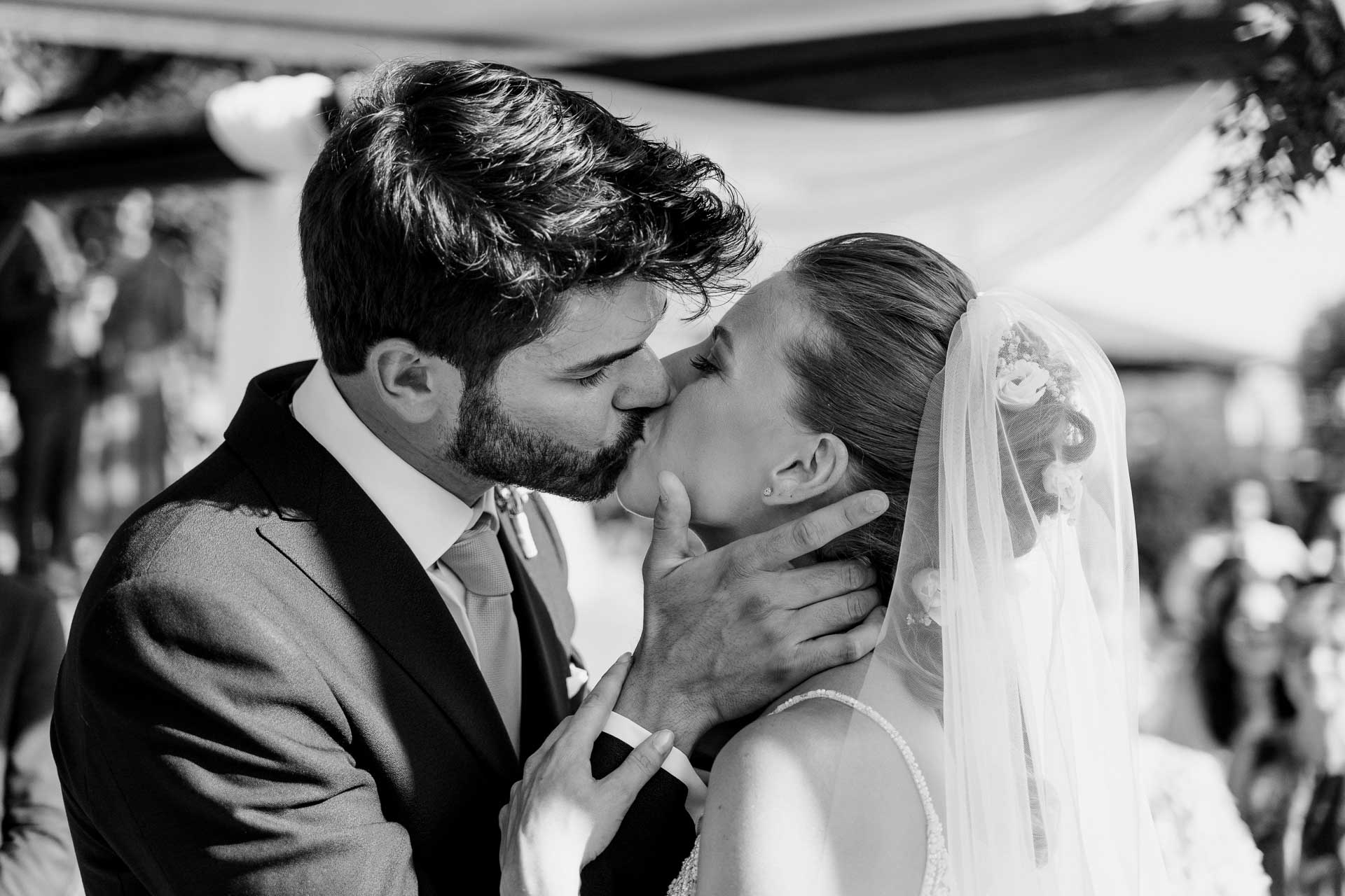 In bianco e nero, il bacio degli sposi sotto il pergolato