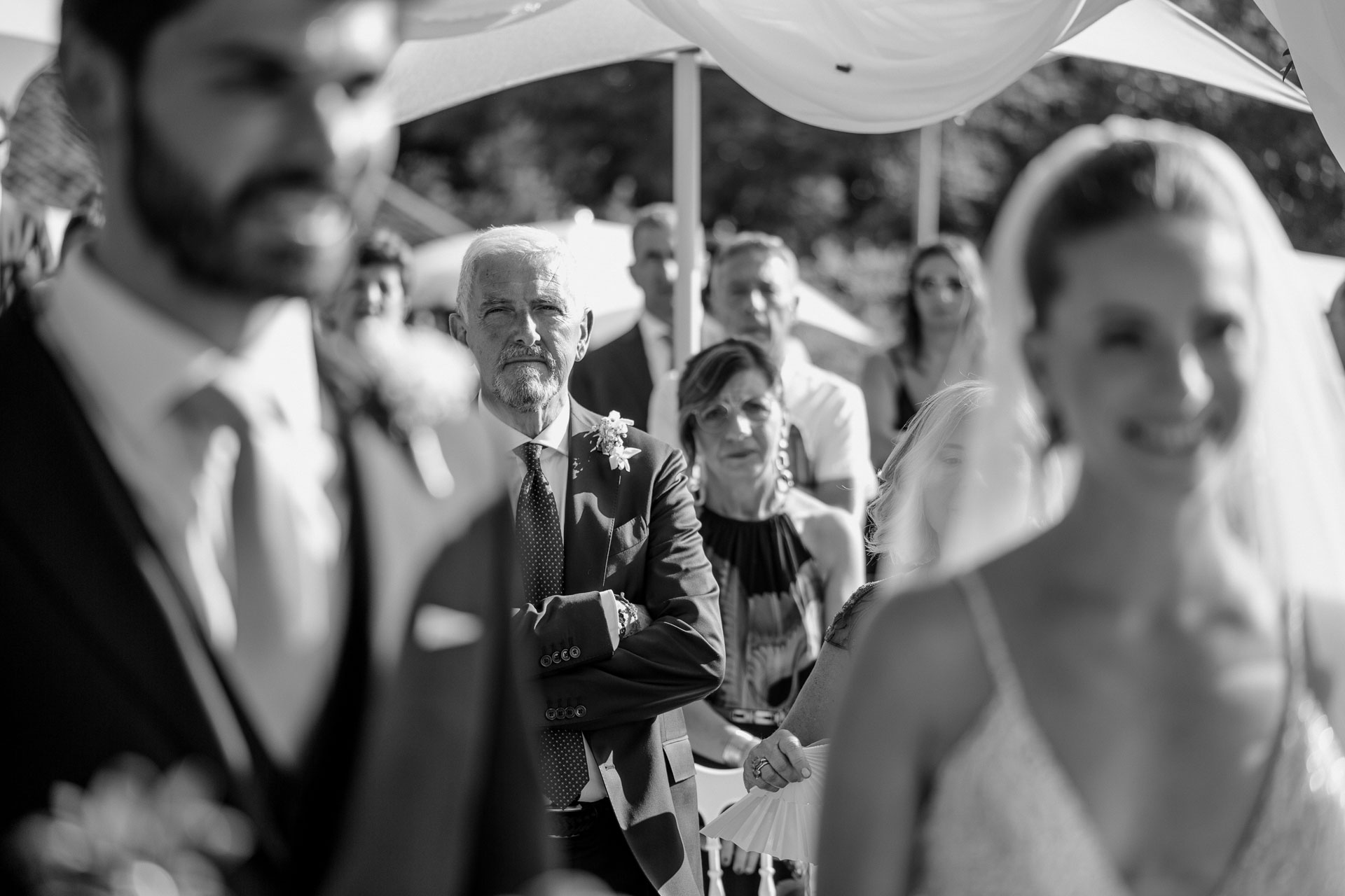In bianco e nero, gli sposi sorridono e gli invitati alle loro spalle