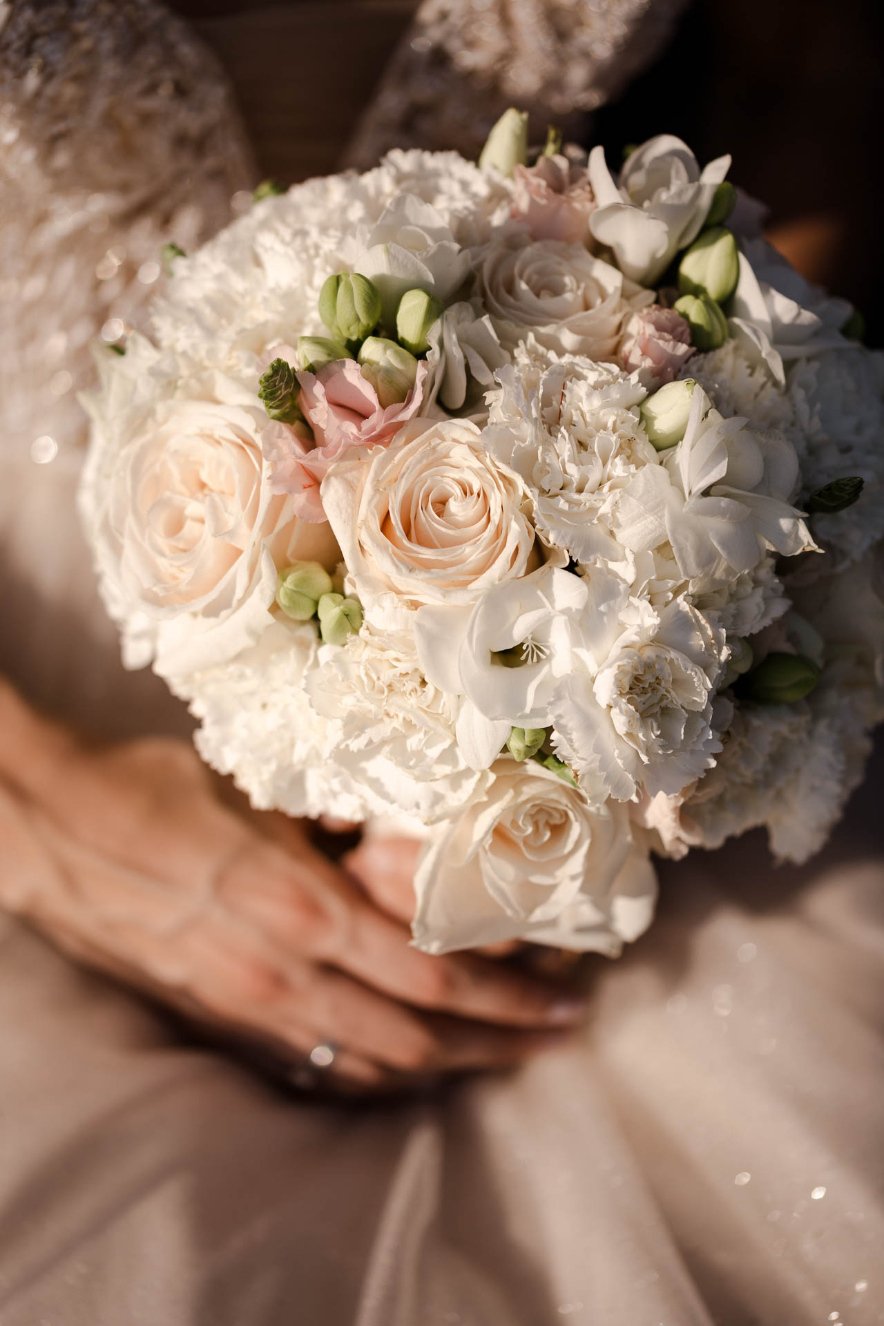 Il bouquet di rose bianche e rosa, stretto tra le mani della sposa