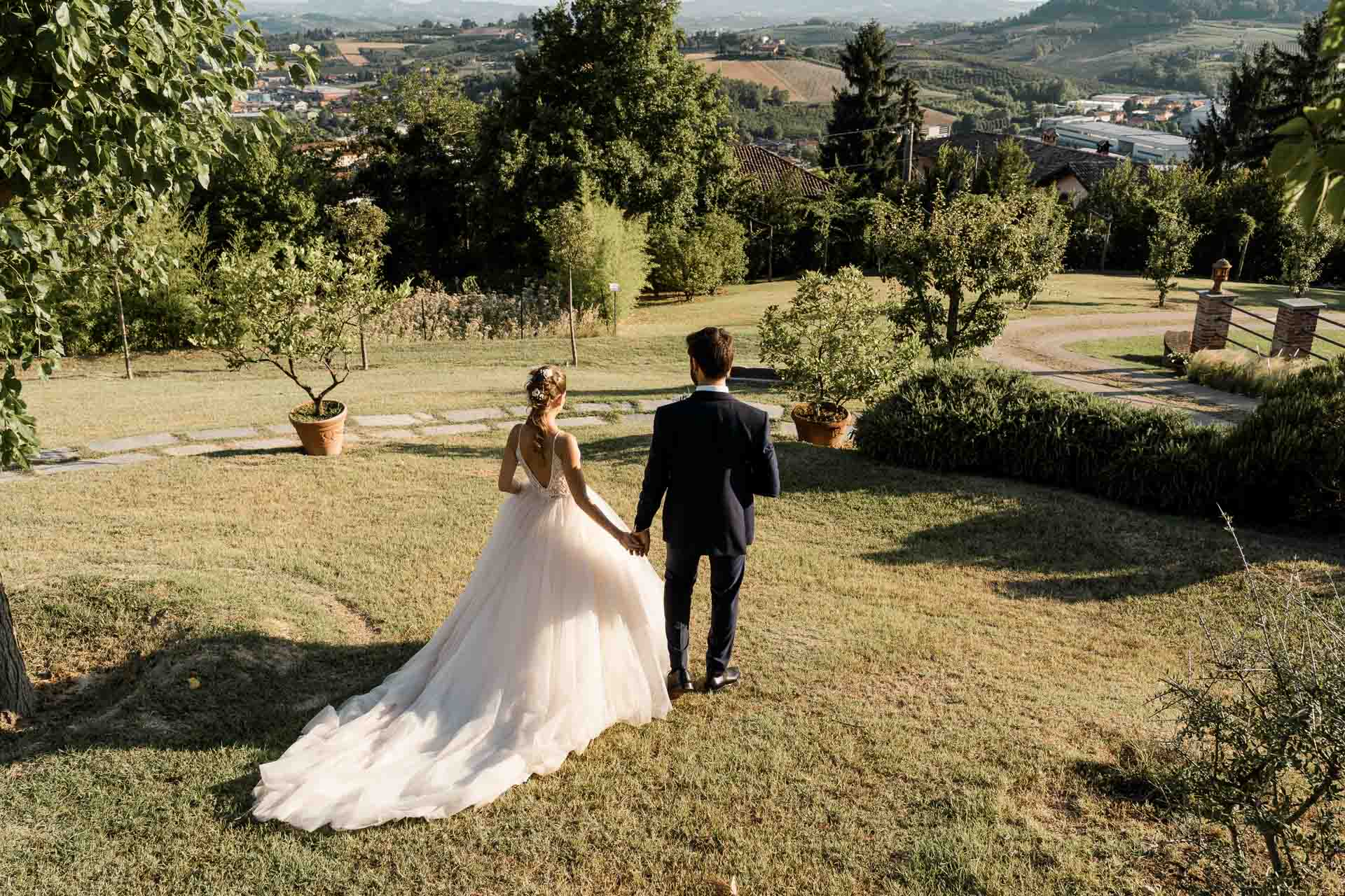 Gli sposi di spalle nel prato del parco, verso le colline del Roero