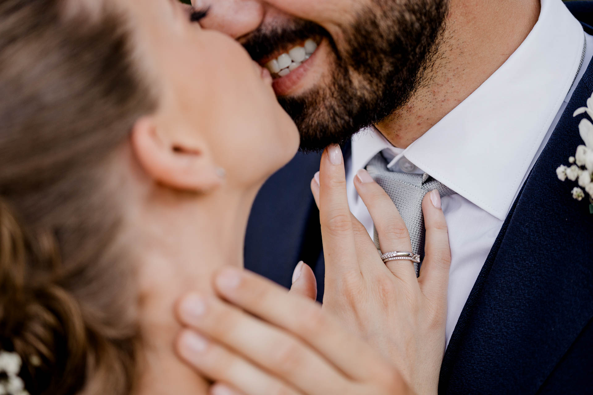 La mano della sposa con la fede sul viso dello sposo, nel bacio