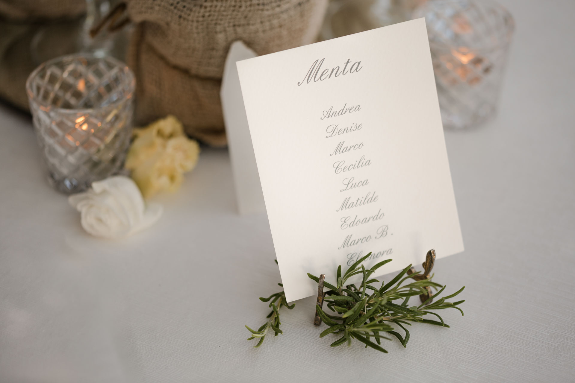 Il segnatavolo "Menta" con i nomi degli invitati, tra rosmarino e candele