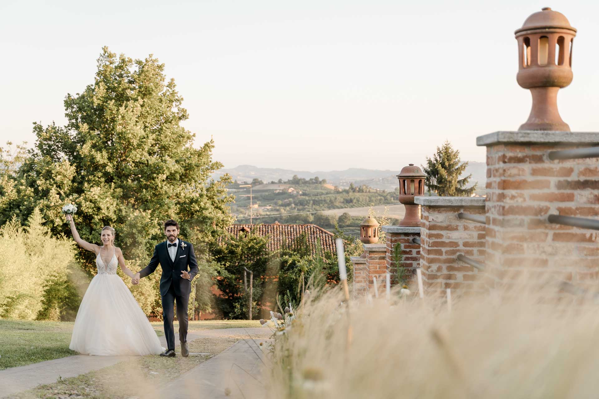 Gli sposi arrivano alla festa con il braccio alzato, e le colline sullo sfondo