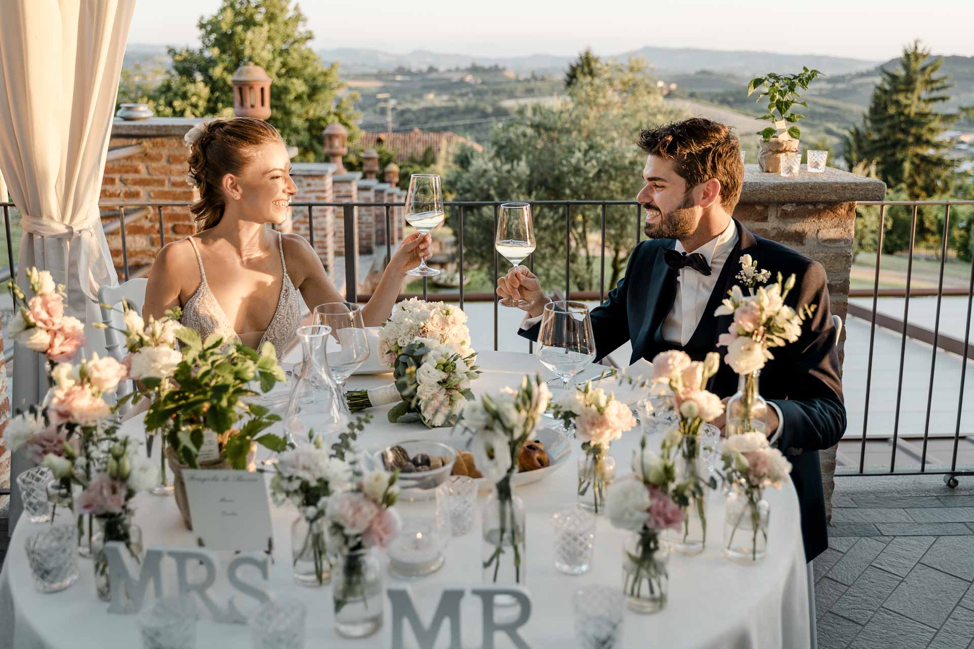 Gli sposi brindano al loro tavolo, con le colline al tramonto