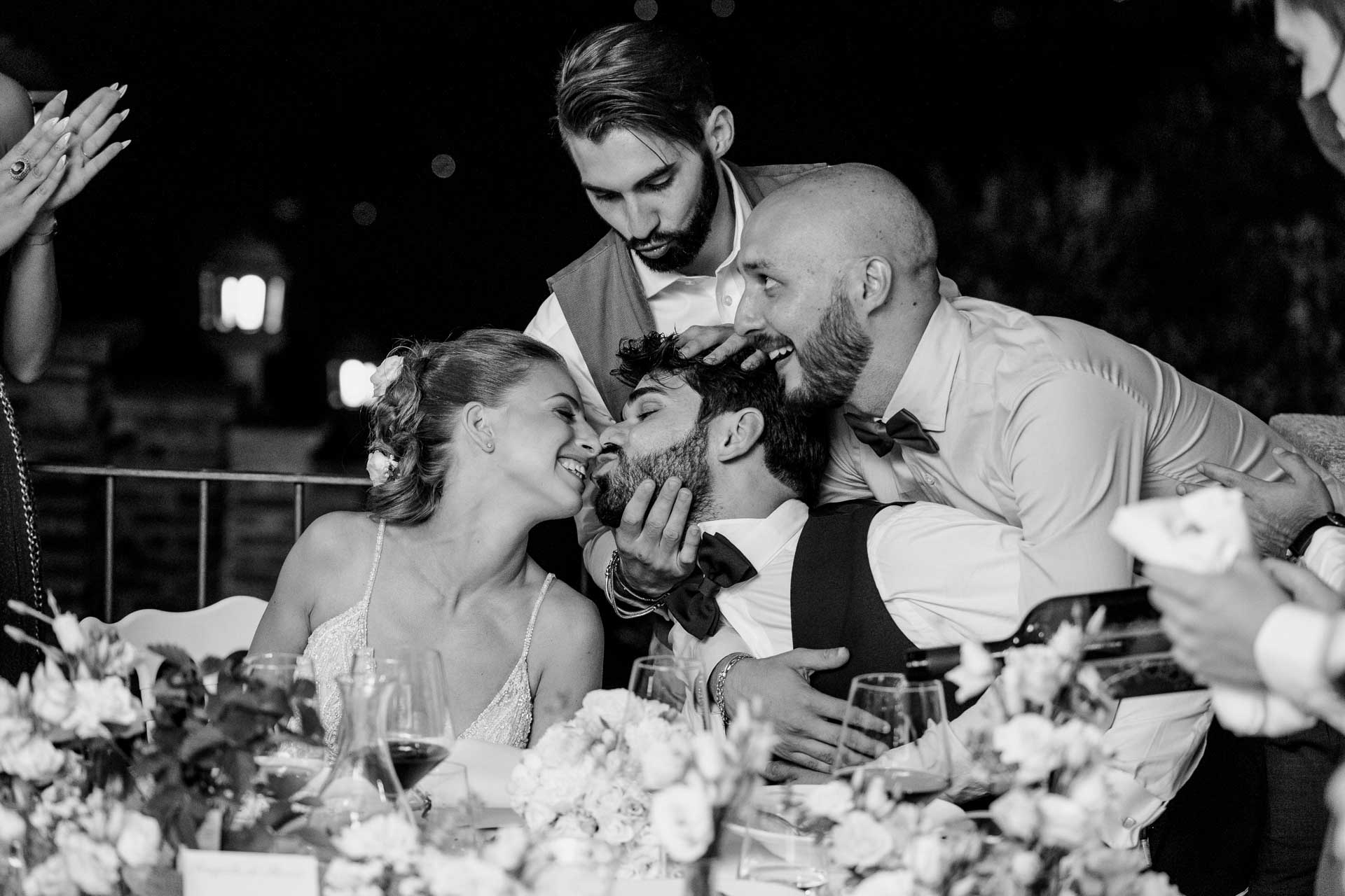 In bianco e nero, gli amici assaltano lo sposo al tavolo e la sposa ride
