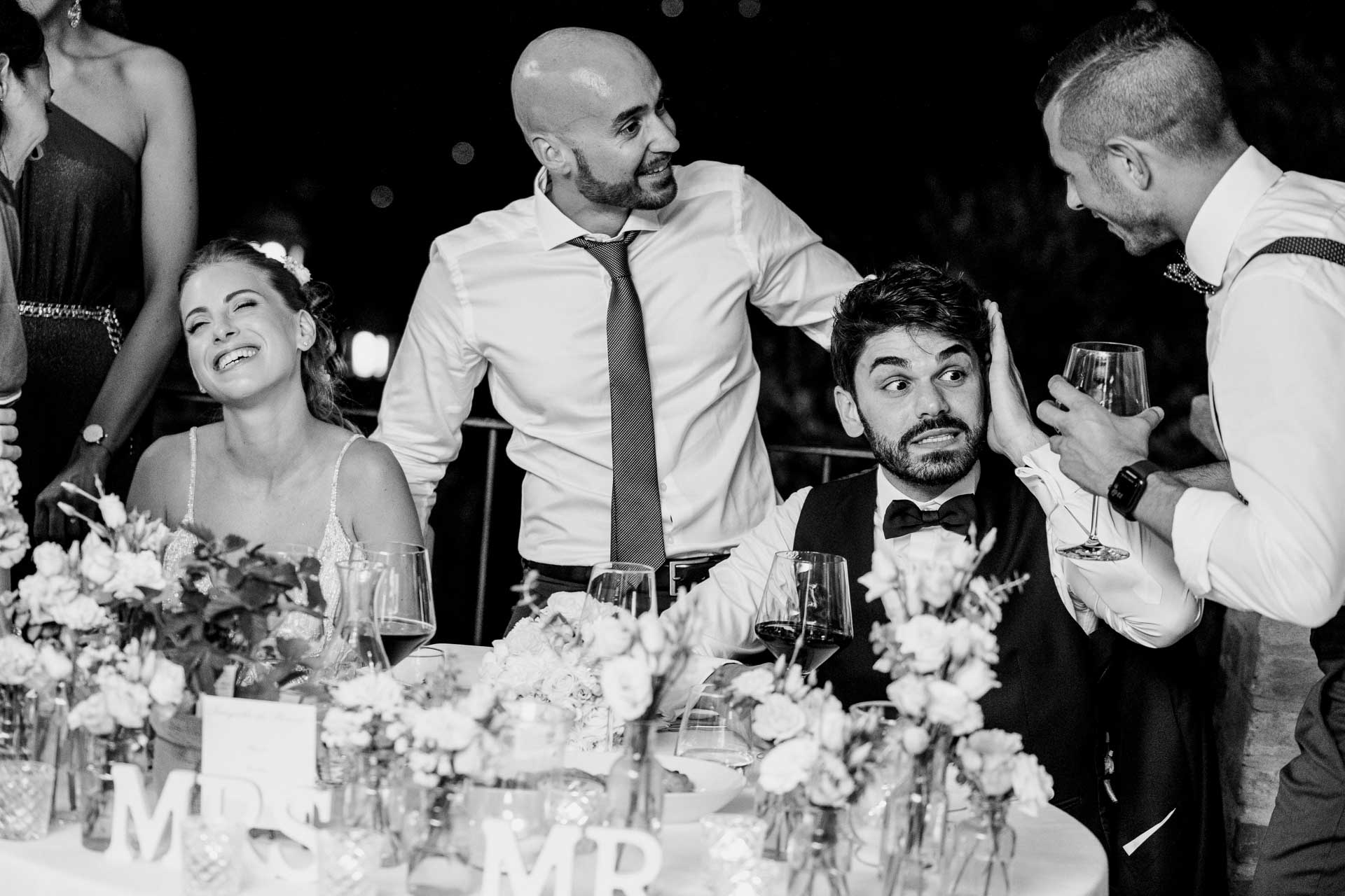 In bianco e nero, gli amici scherzano con lo sposo e la sposa ride