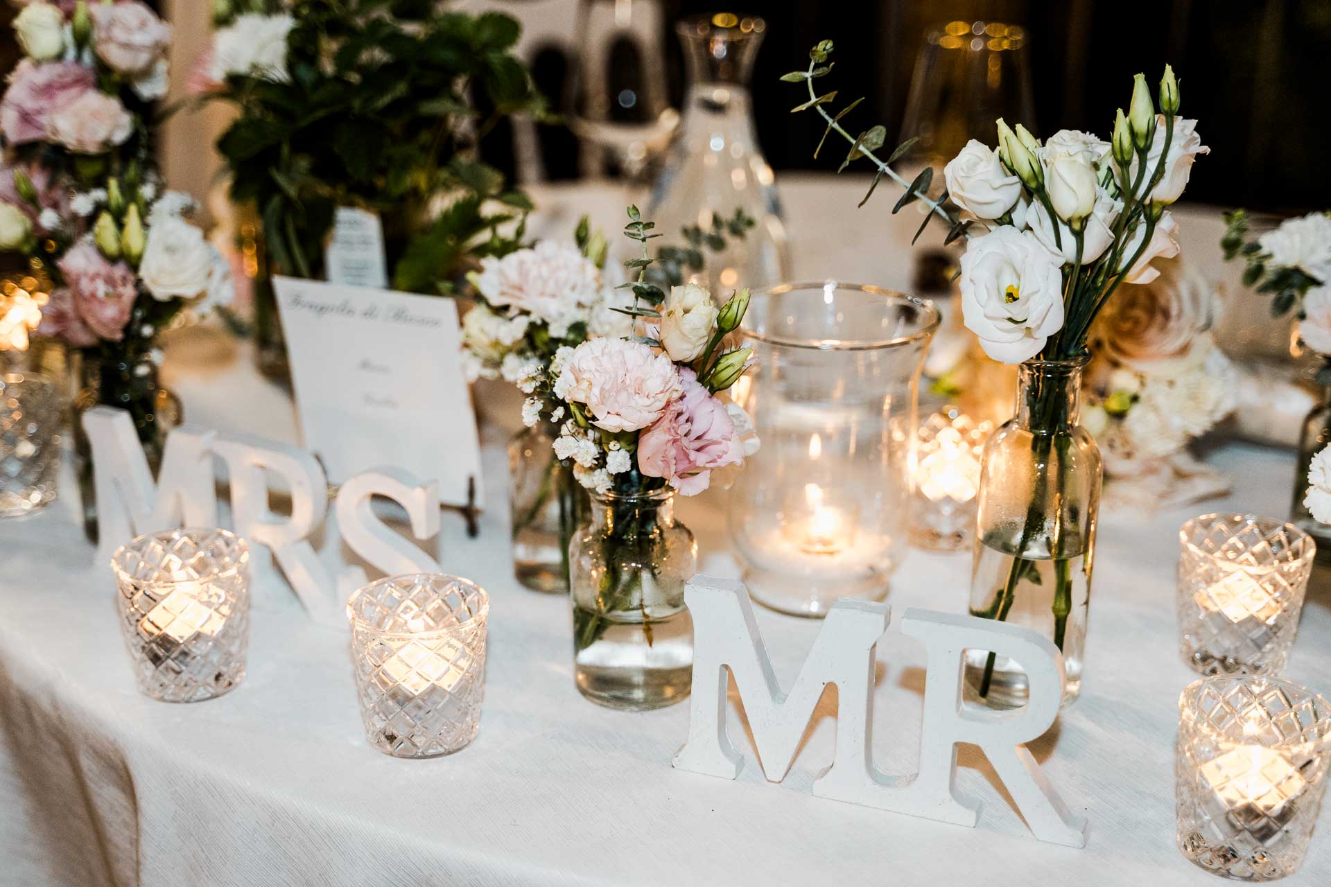 Il tavolo degli sposi di sera, con le candele e le lettere MRS e MR