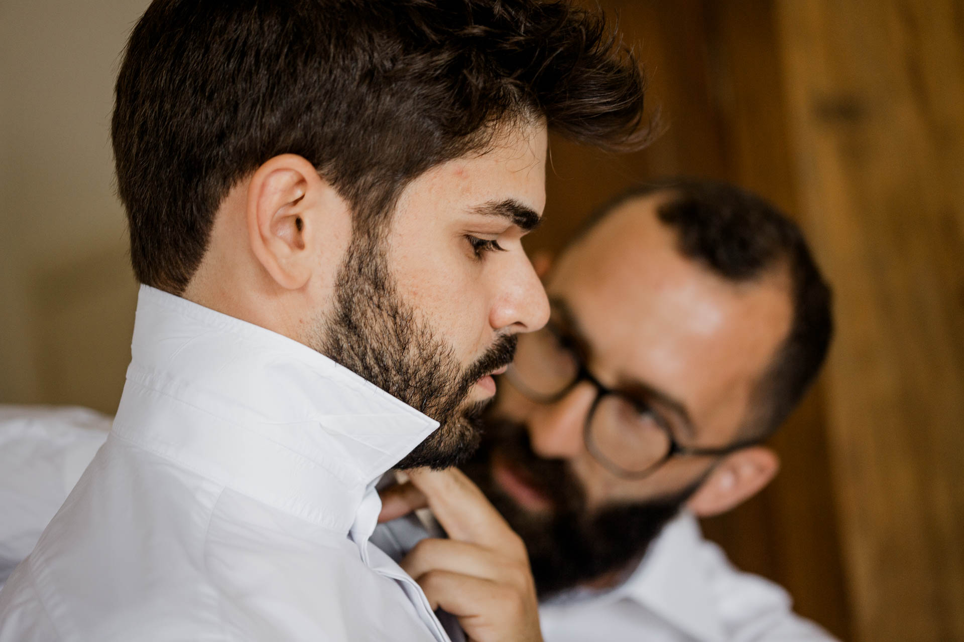 L'amico sistema il colletto allo sposo, sguardo concentrato