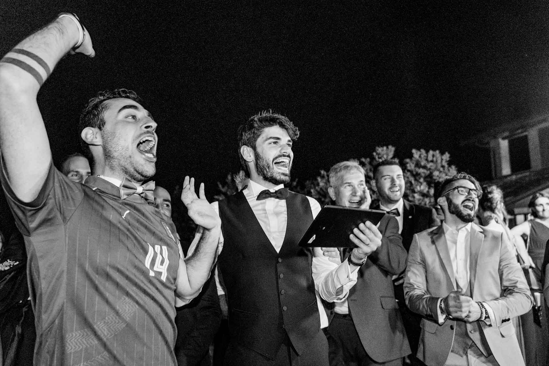 In bianco e nero, gli invitati esultano, un amico in maglia da calcio