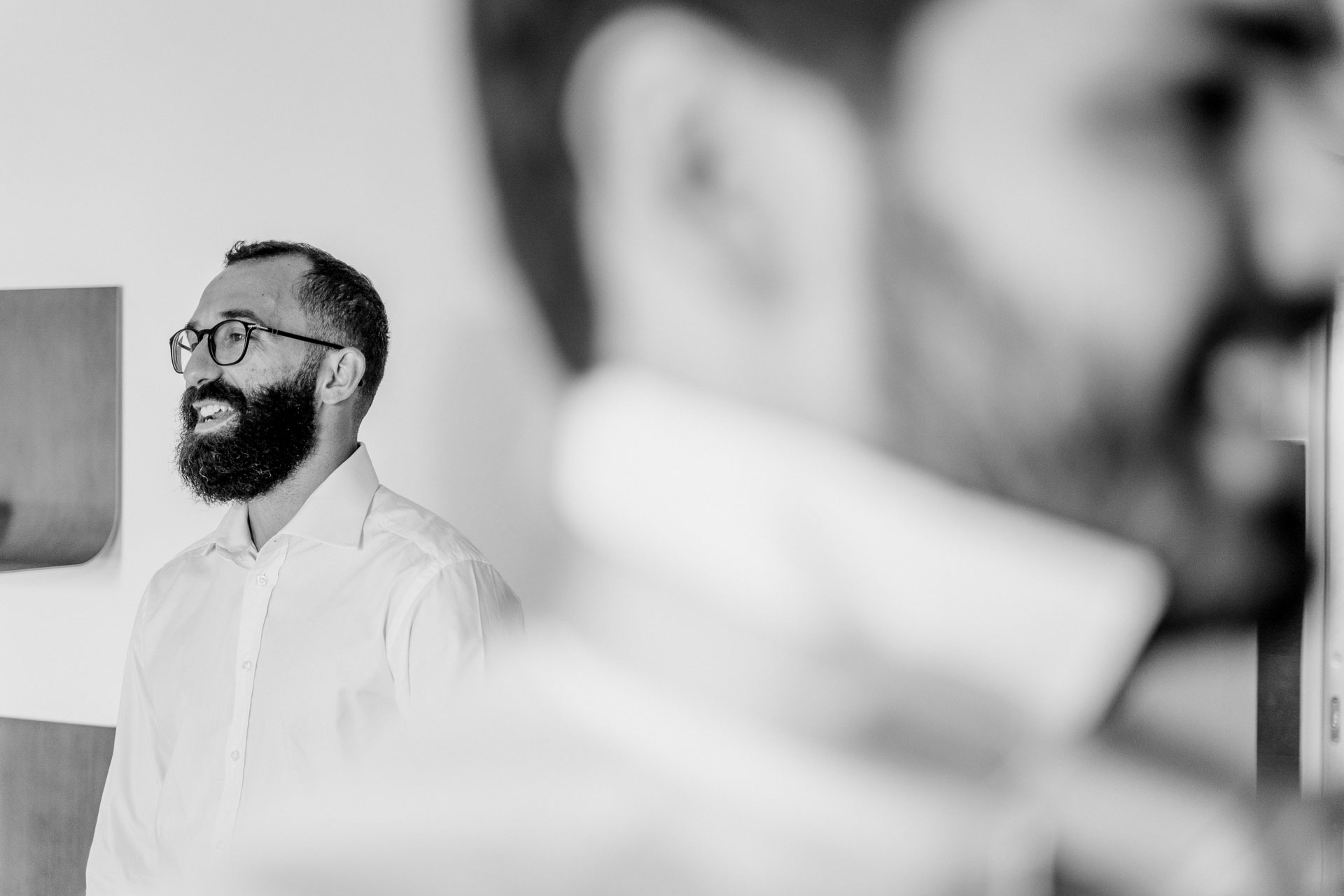 In bianco e nero, l'amico sorride sullo sfondo mentre lo sposo si prepara