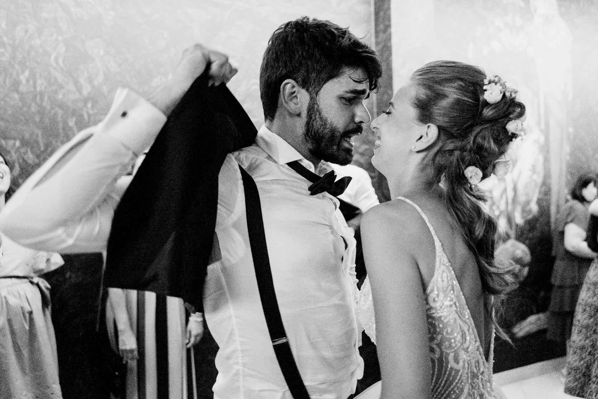 In bianco e nero, lo sposo in bretelle e la sposa in pista, e una giacca che vola