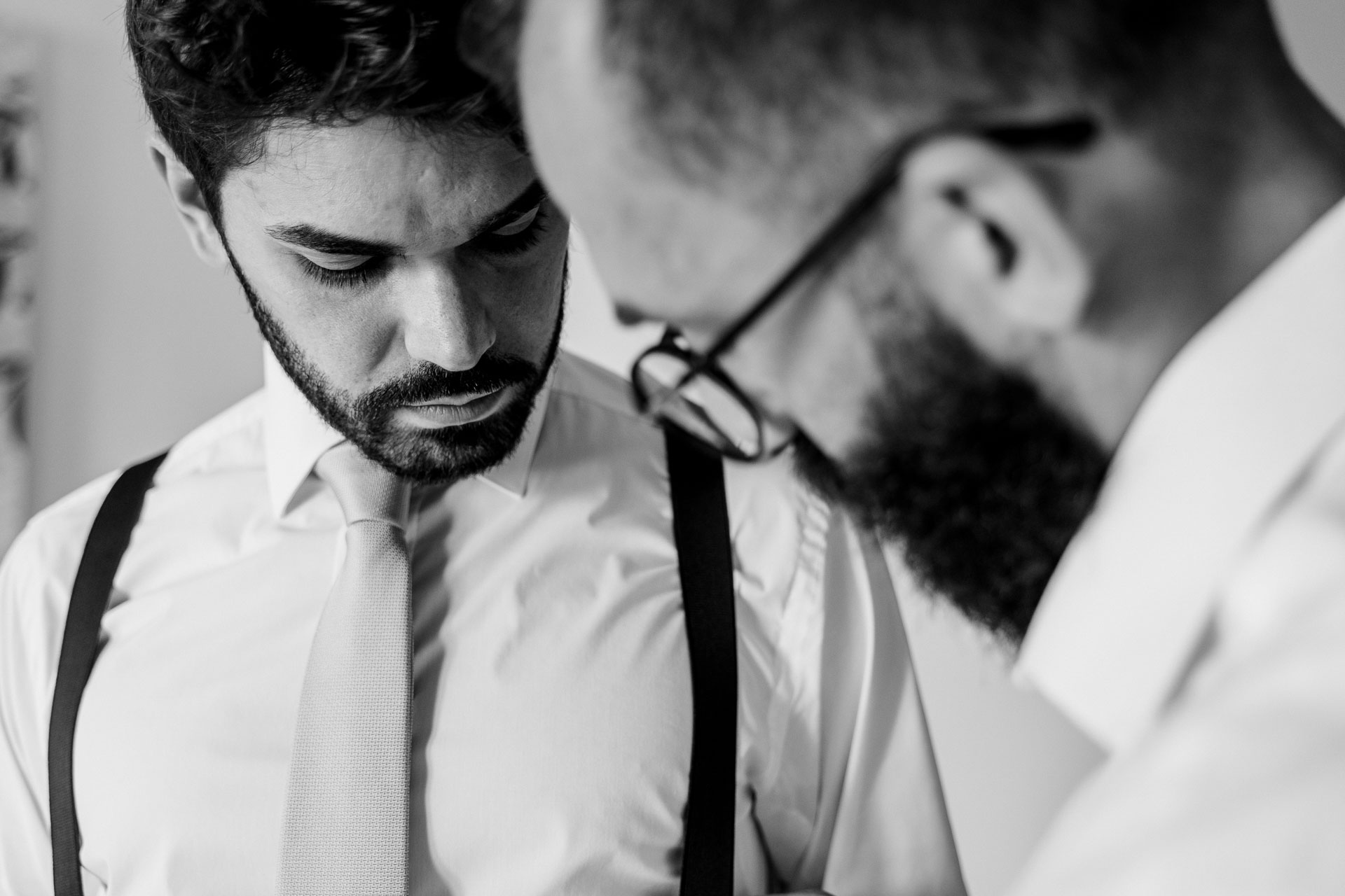 In bianco e nero, la cravatta chiara e le bretelle: l'ultimo ritocco dell'amico