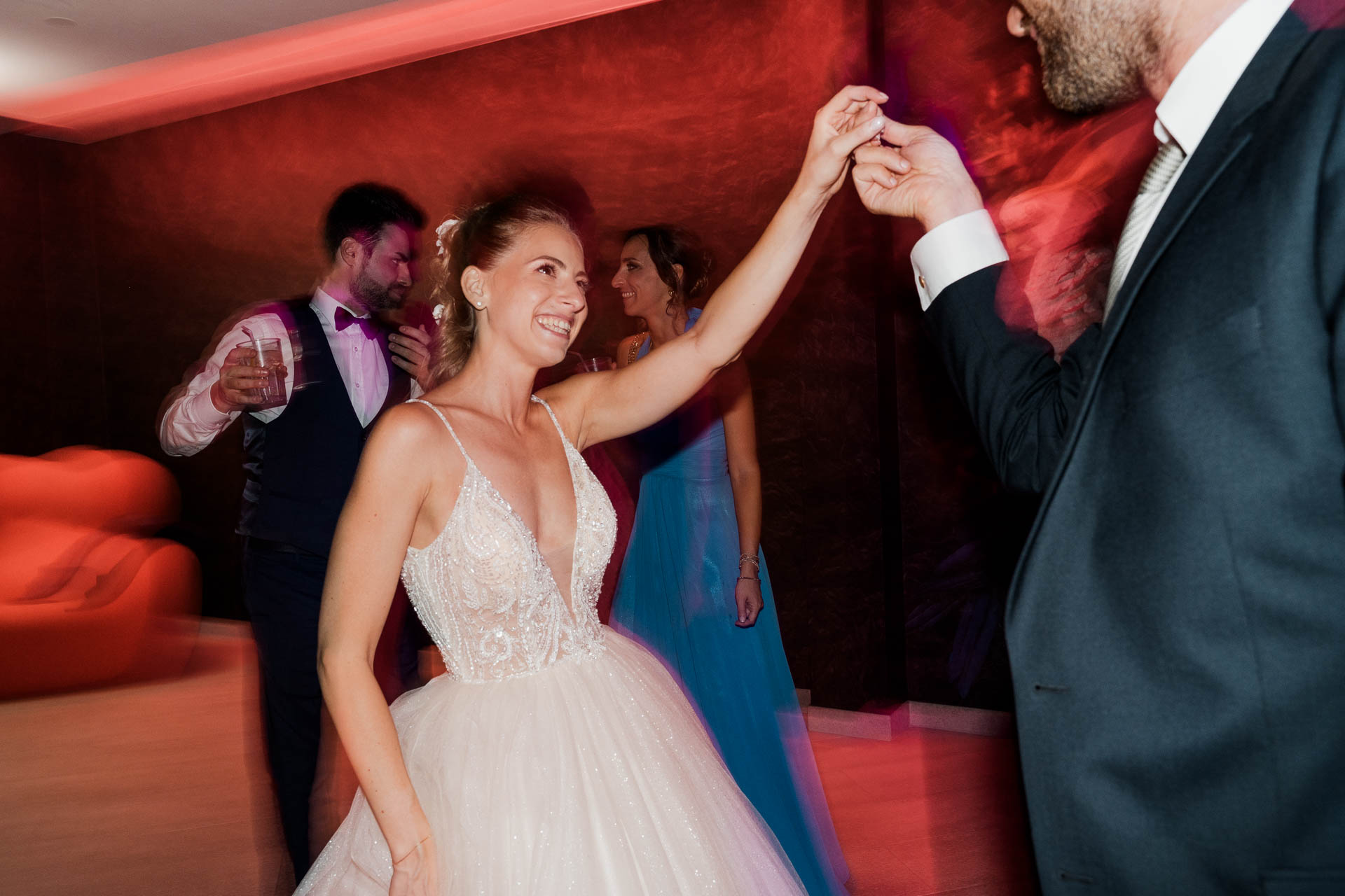 La sposa balla con il braccio alzato, nelle luci rosse