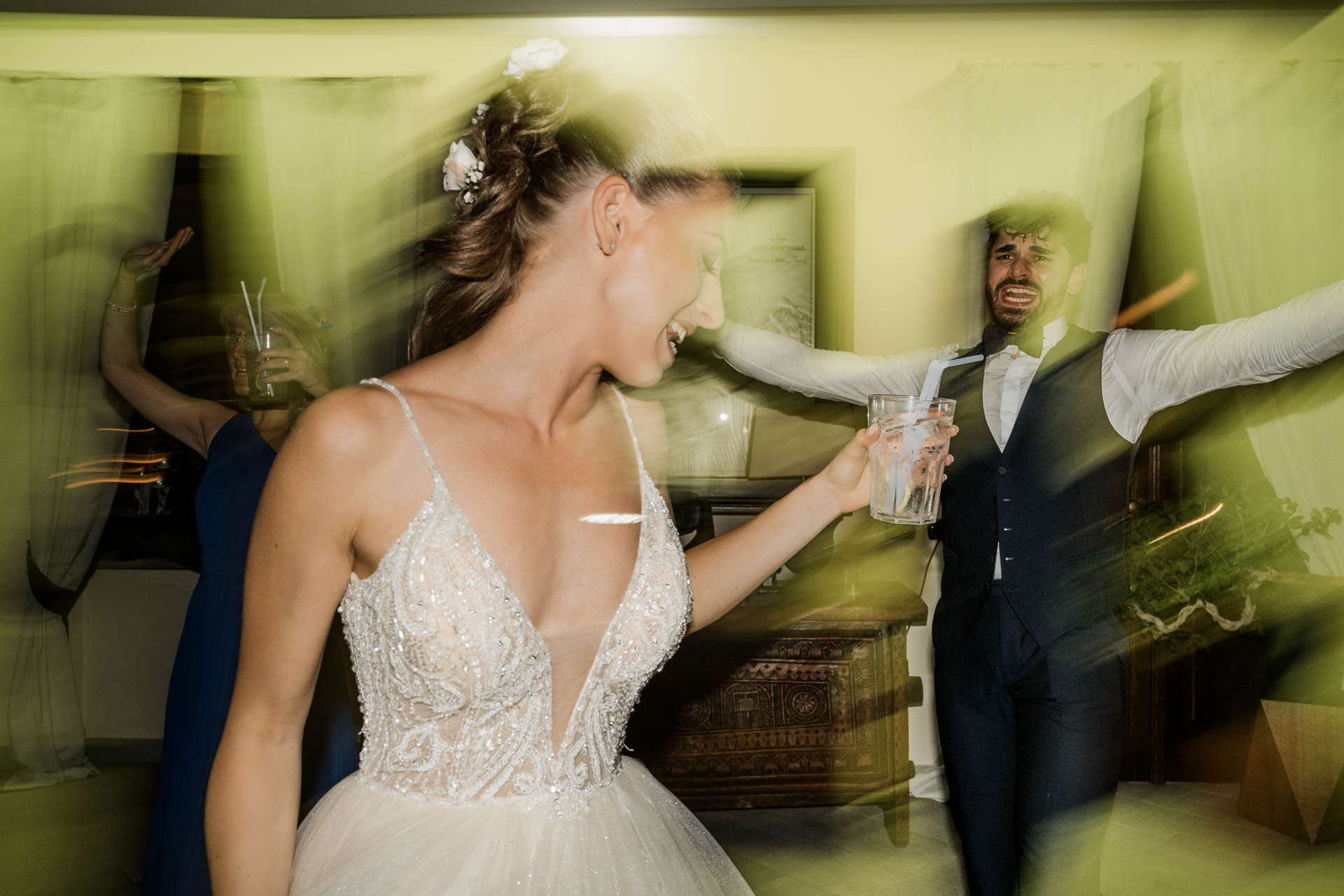 La sposa balla e lo sposo dietro di lei, nella luce gialla in movimento