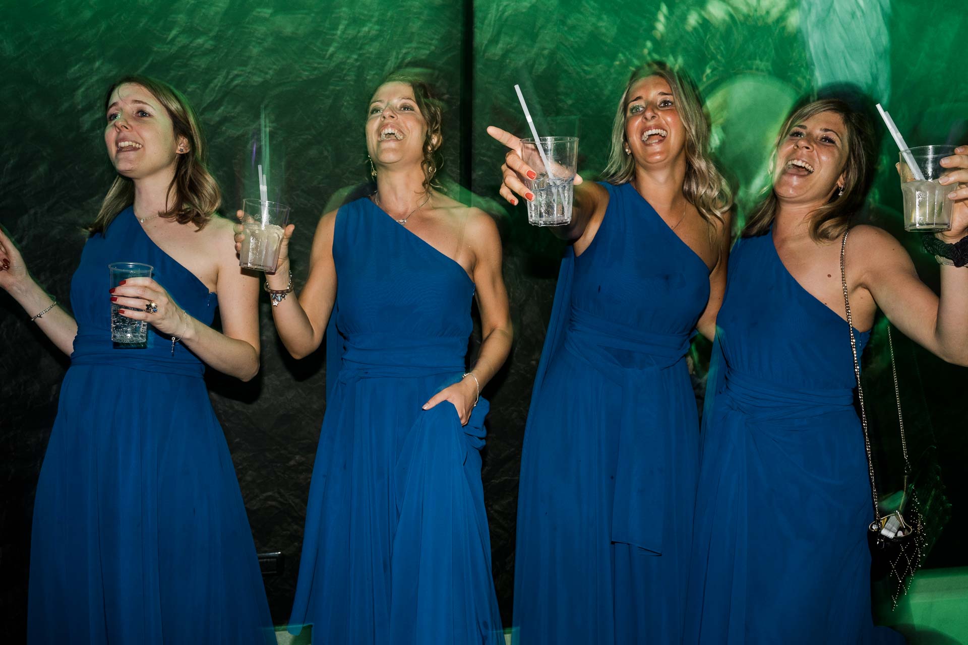 Le amiche in blu ballano e cantano con il bicchiere in mano