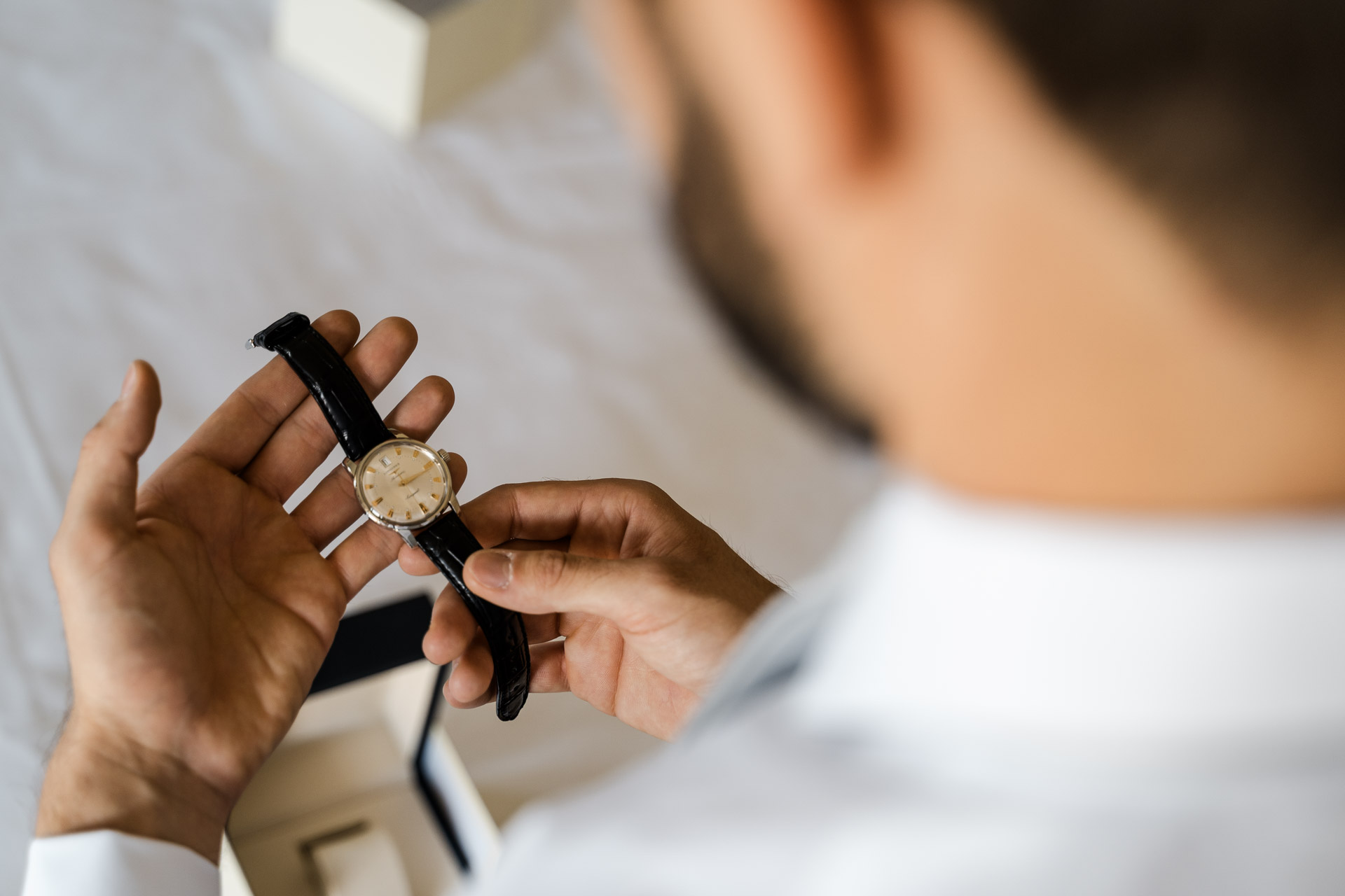 Le mani dello sposo con l'orologio dal cinturino di pelle