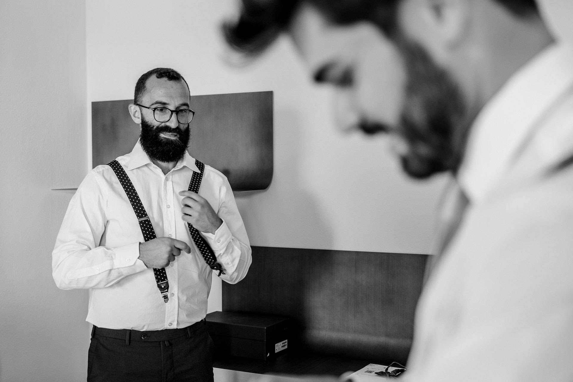 In bianco e nero, l'amico con le bretelle a pois e lo sposo in primo piano