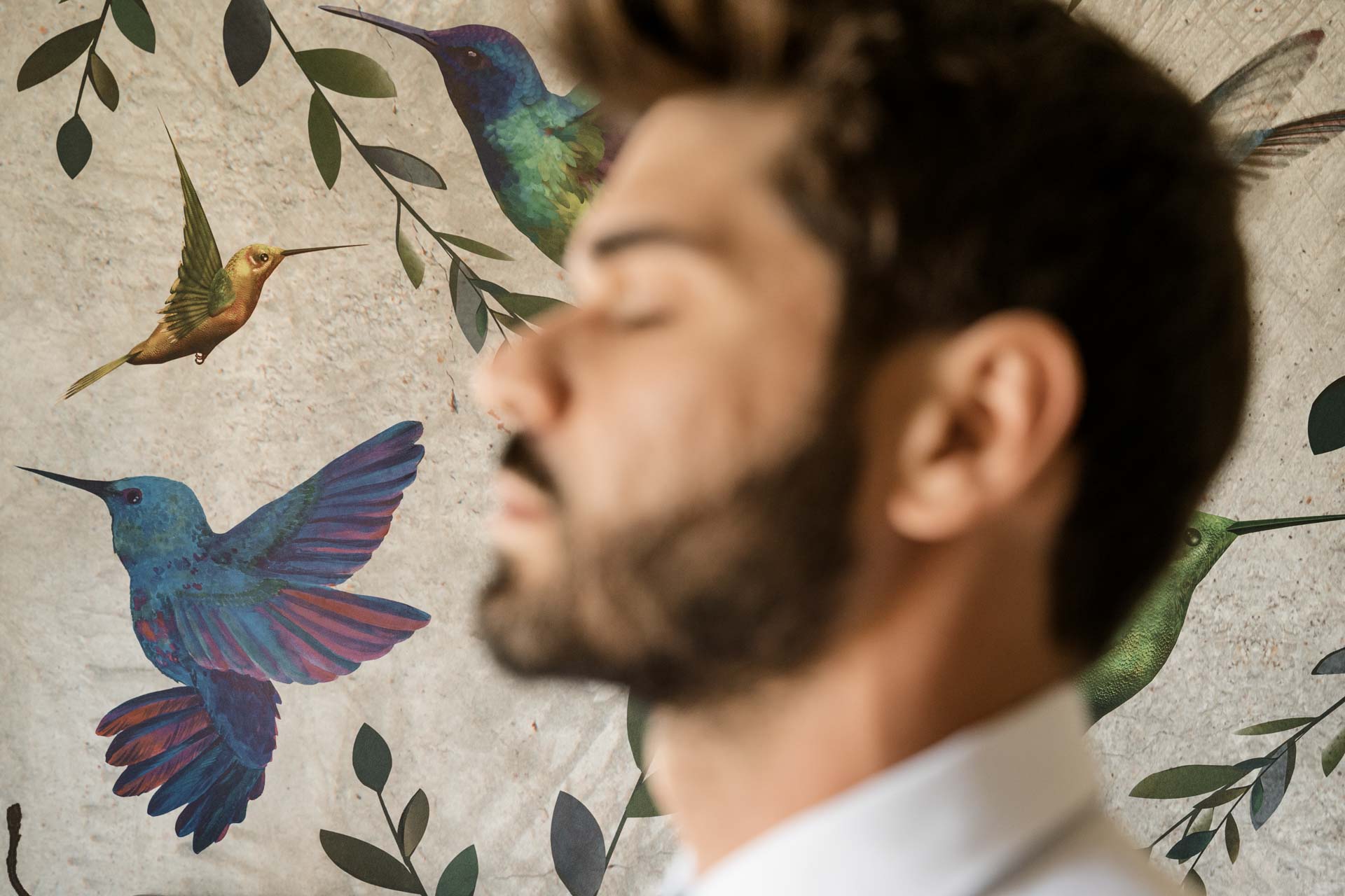 Lo sposo a occhi chiusi davanti al muro dipinto a colibrì