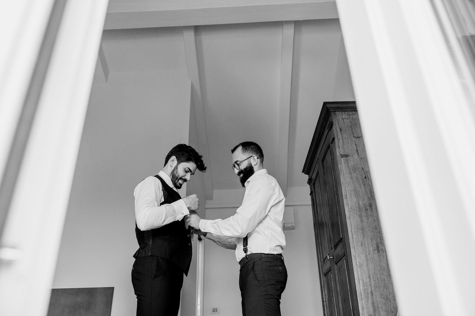 In bianco e nero, lo sposo e l'amico nella stanza, visti dalla porta