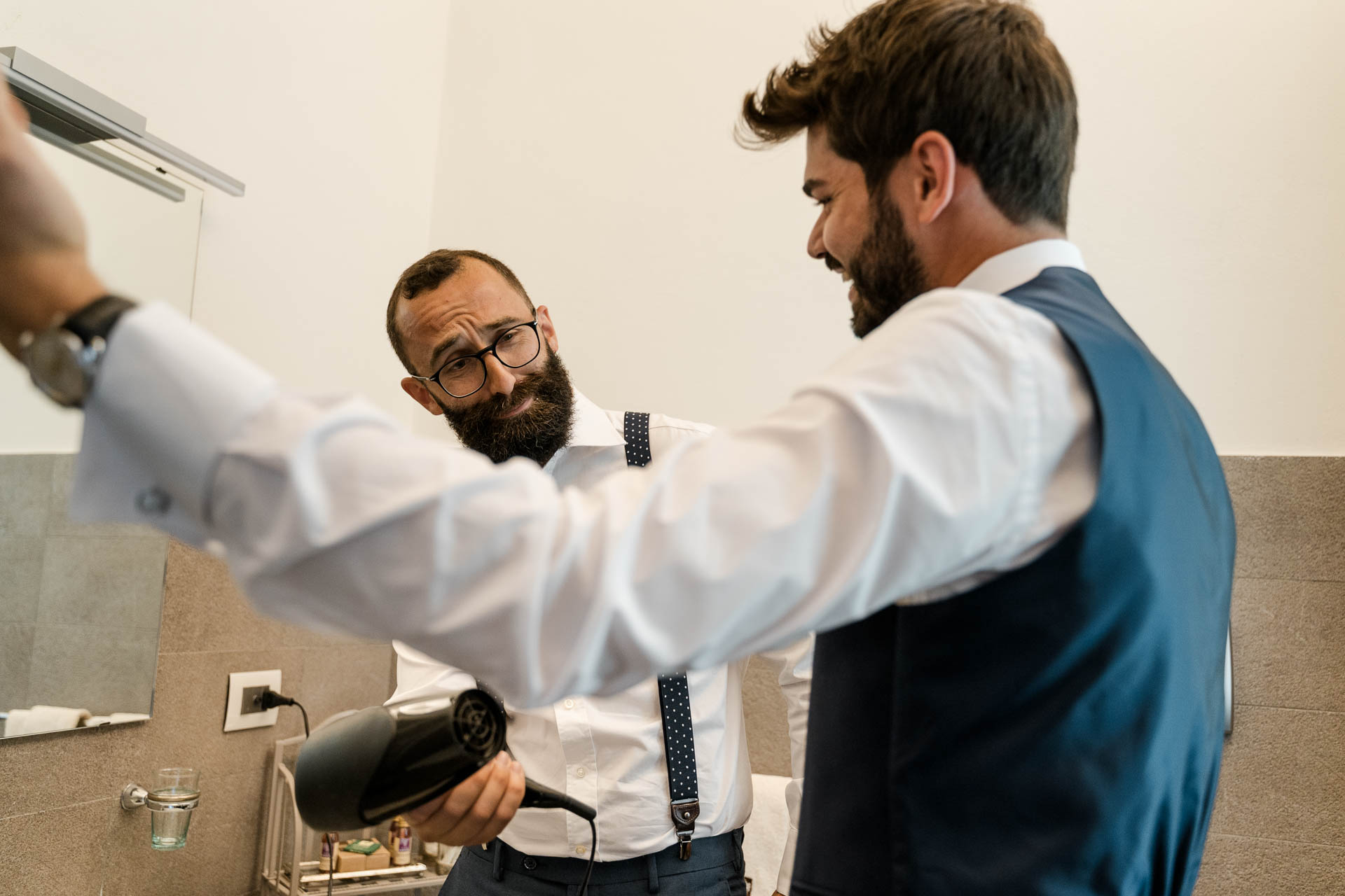 L'amico con il phon in mano e lo sposo davanti allo specchio del bagno