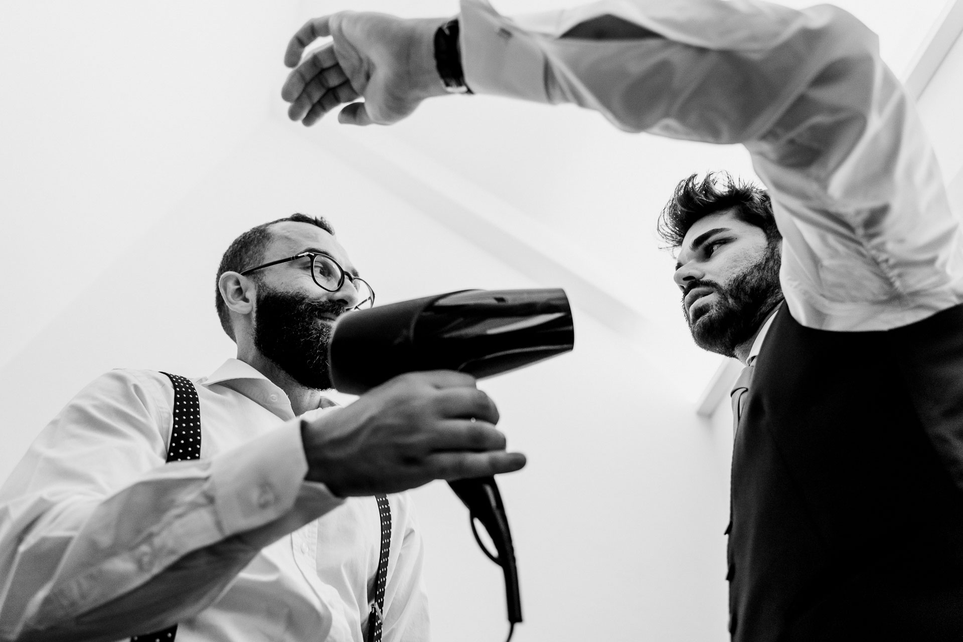 In bianco e nero, l'amico punta il phon sui capelli dello sposo
