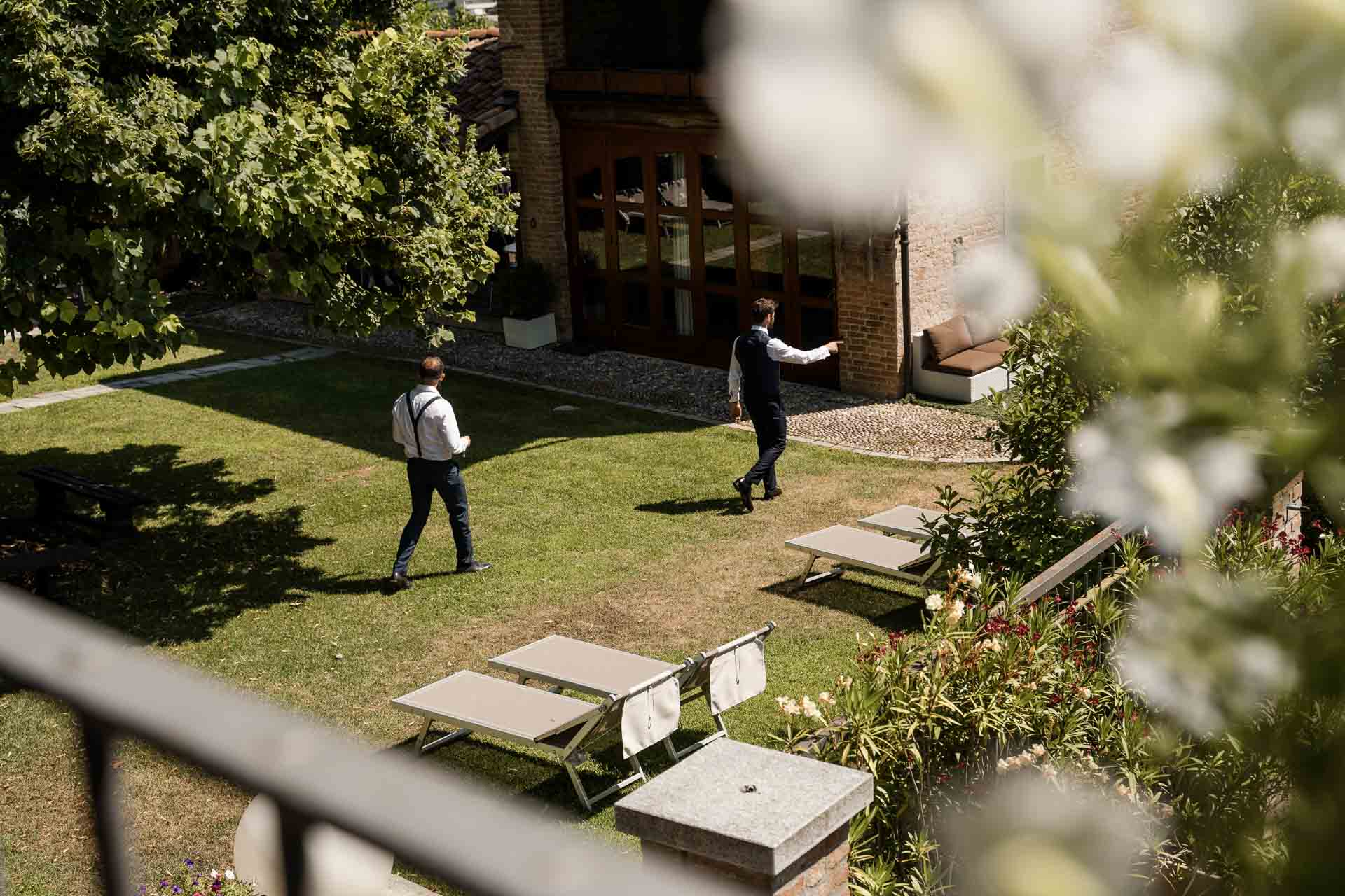 Lo sposo e l'amico attraversano il prato, visti dall'alto tra i fiori bianchi