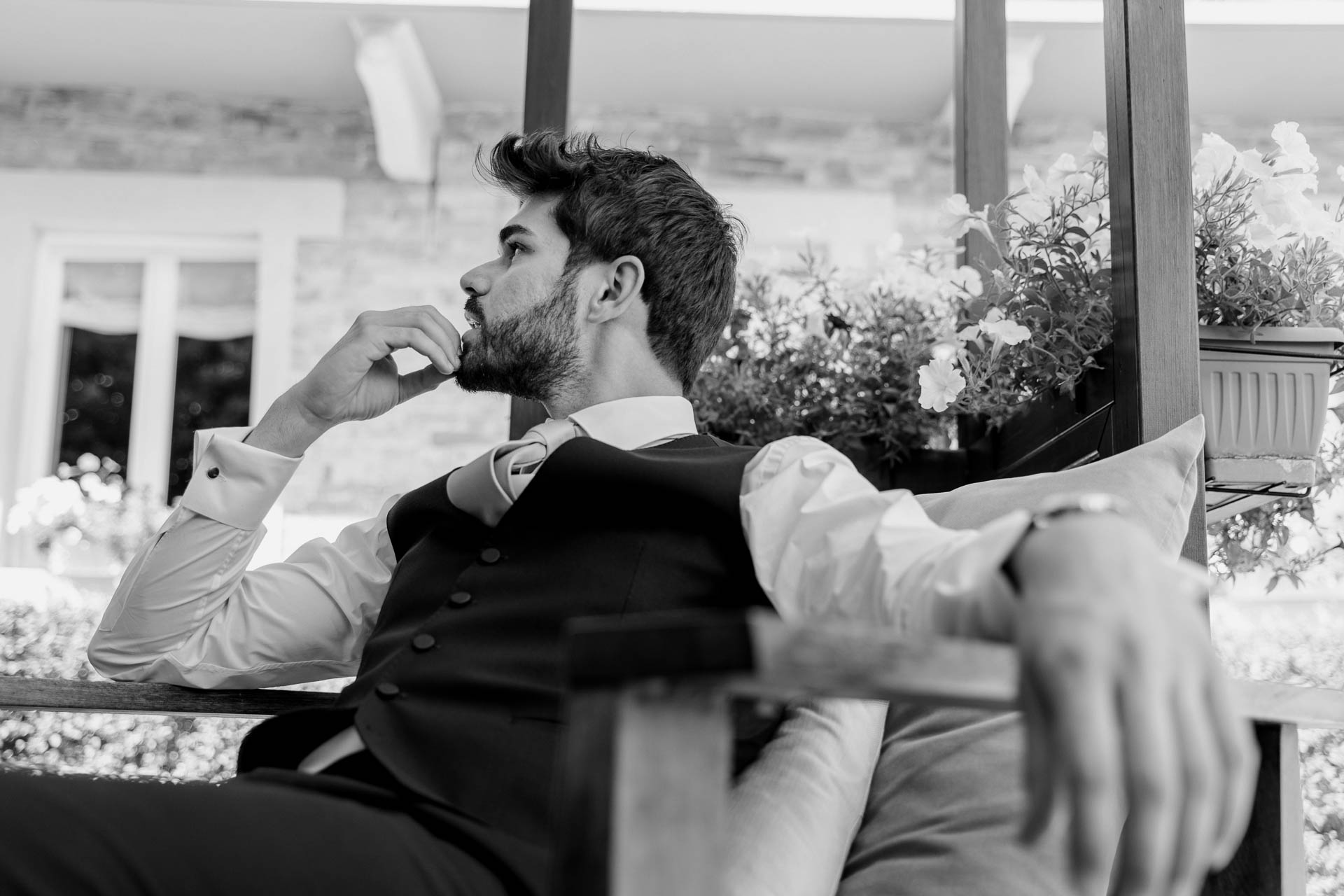 In bianco e nero, lo sposo pensieroso sotto il pergolato, la mano al mento