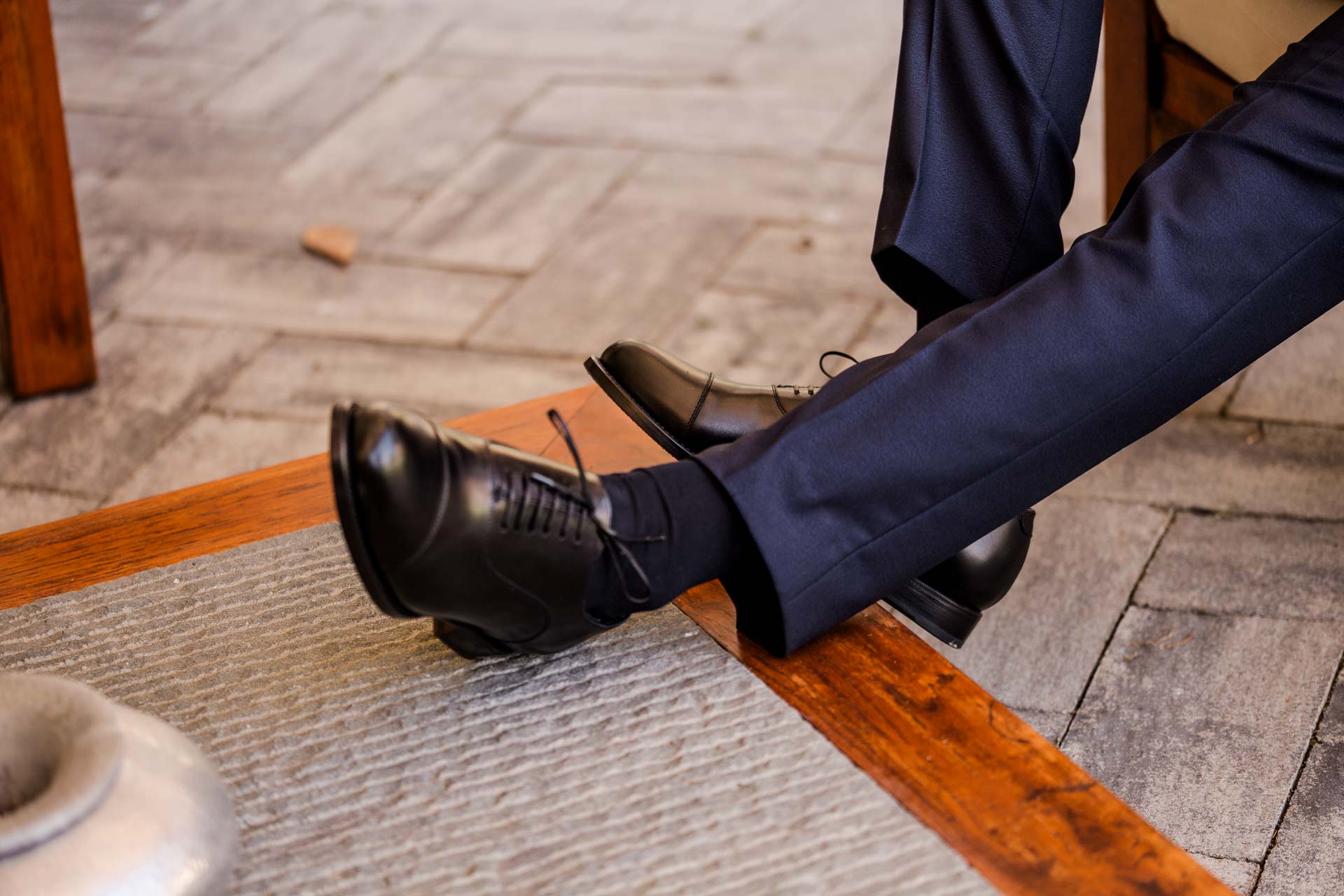 Le scarpe nere dello sposo e il pantalone blu sul pavimento di cotto