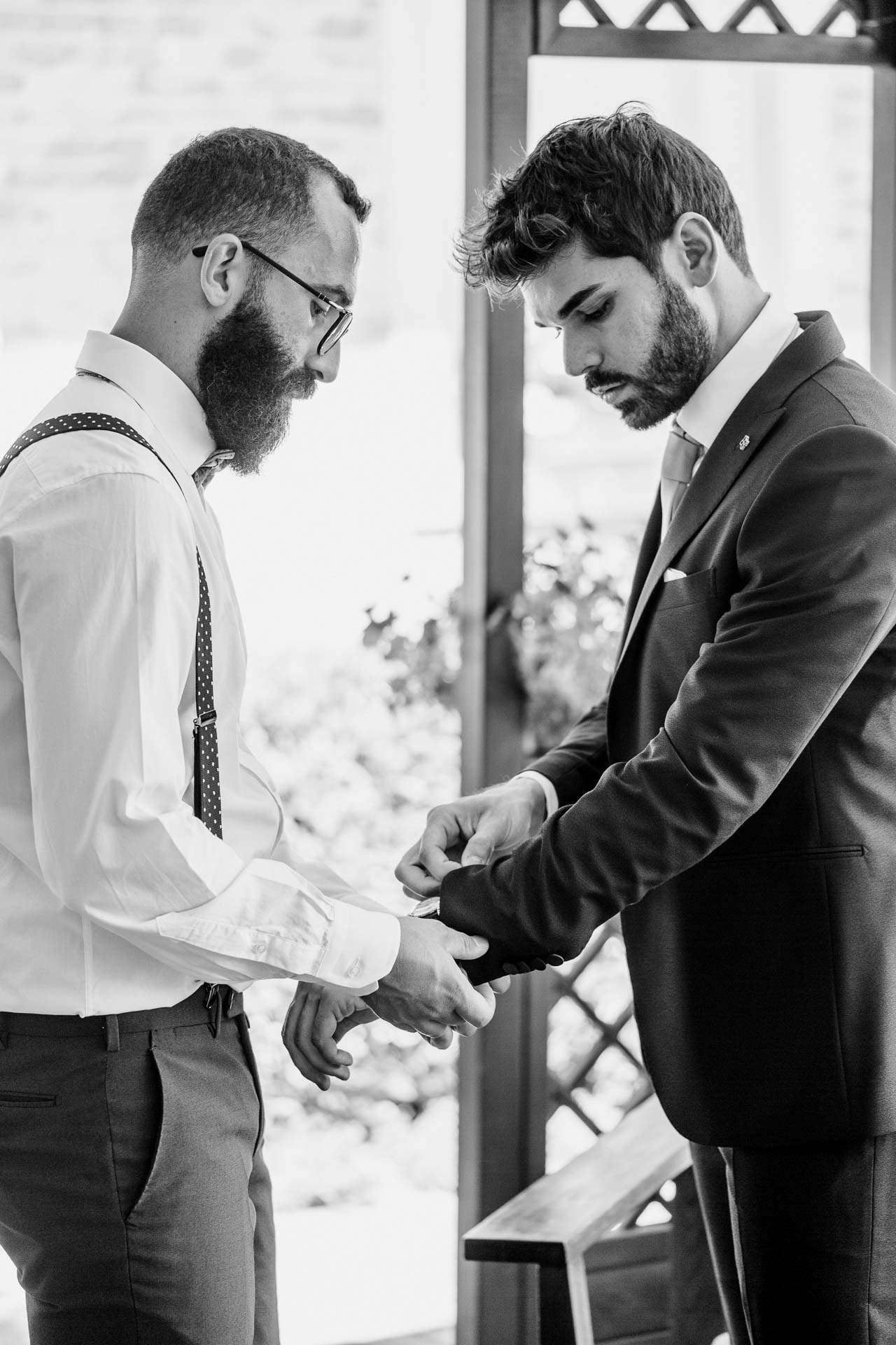 In bianco e nero, l'amico sistema la manica della giacca allo sposo