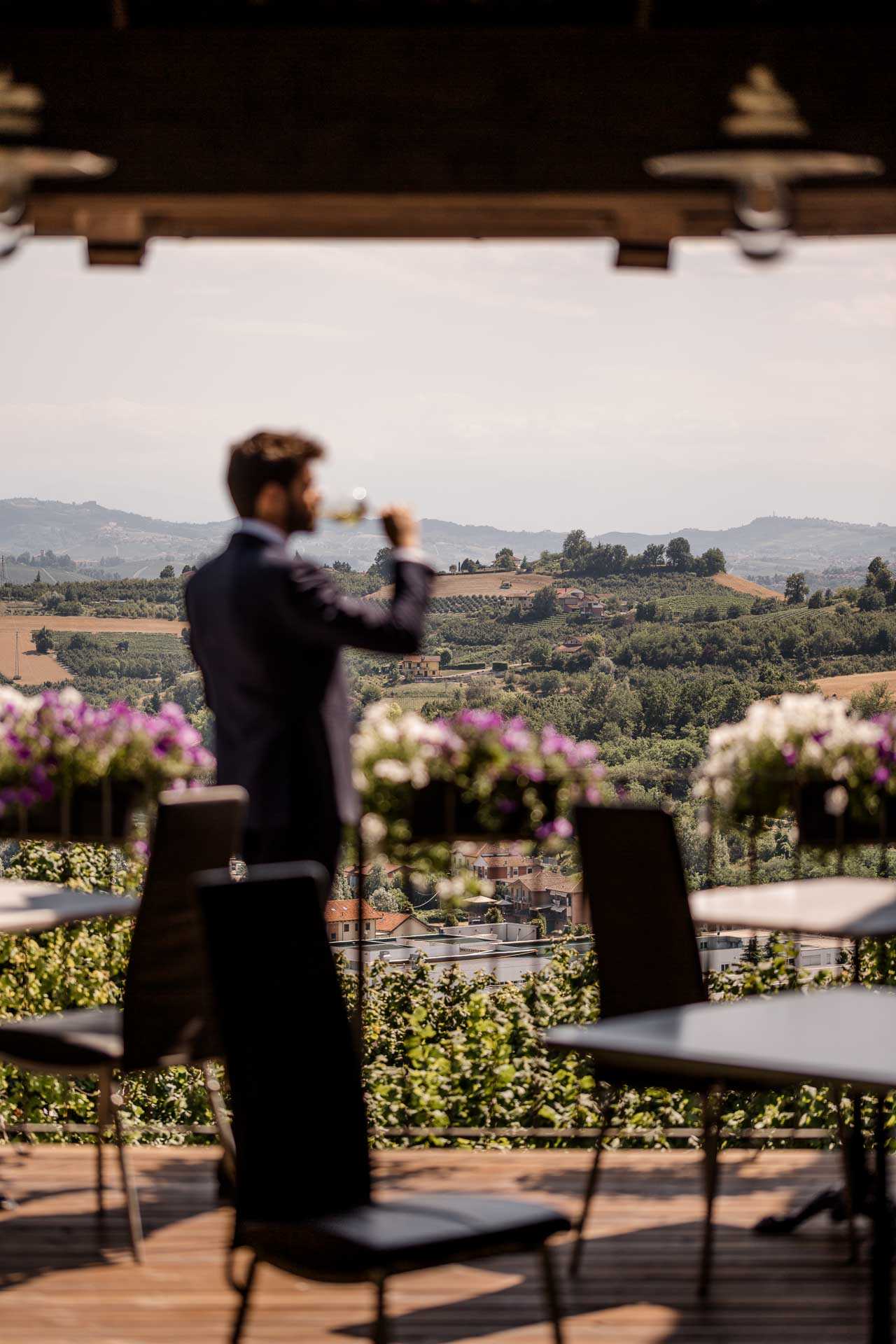 Lo sposo brinda da solo sulla terrazza, con le vigne e le colline del Roero davanti