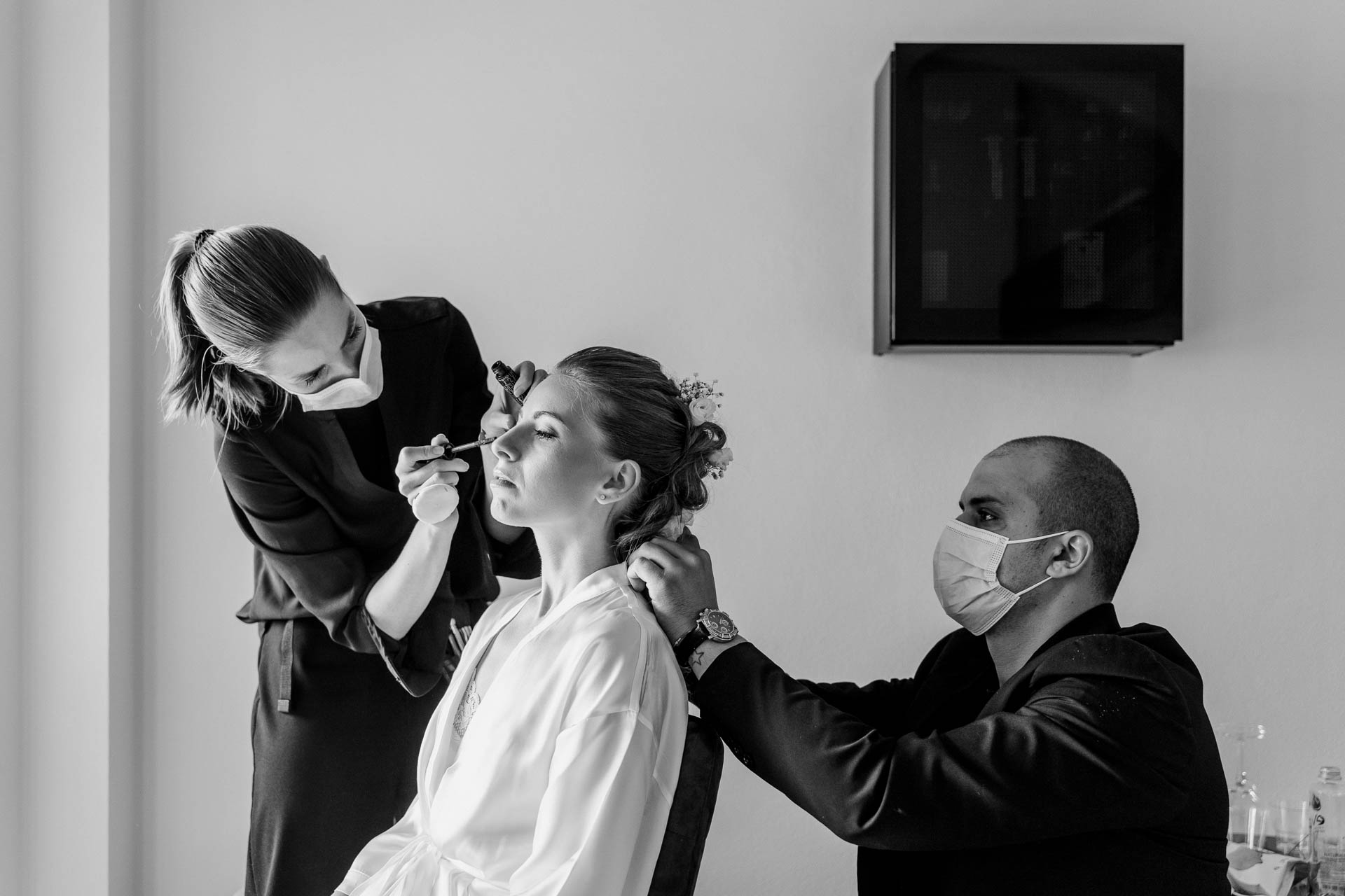 In bianco e nero, la sposa tra la truccatrice e il parrucchiere