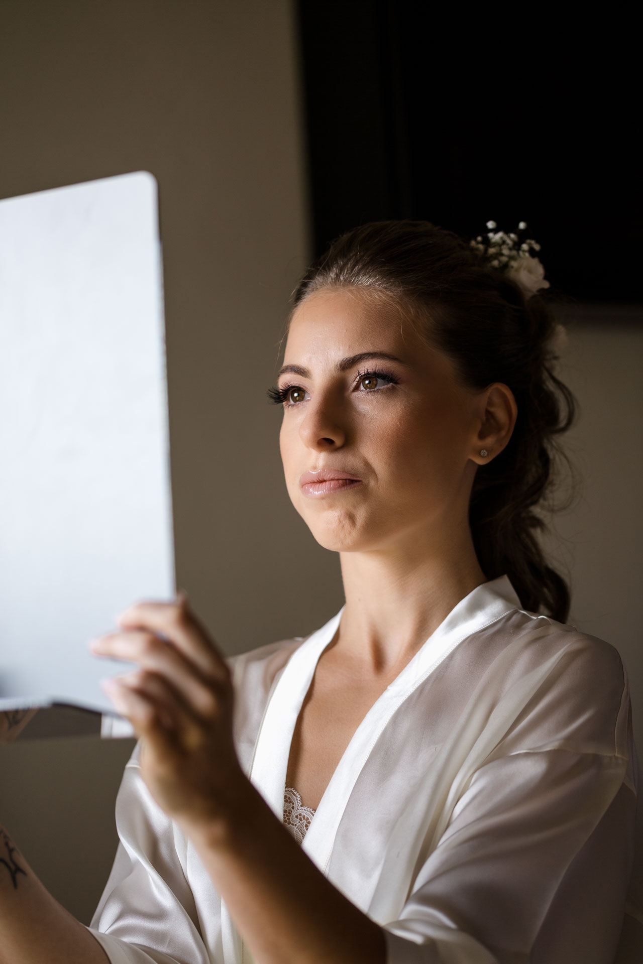 La sposa si guarda nello specchio a mano, con i fiori tra i capelli