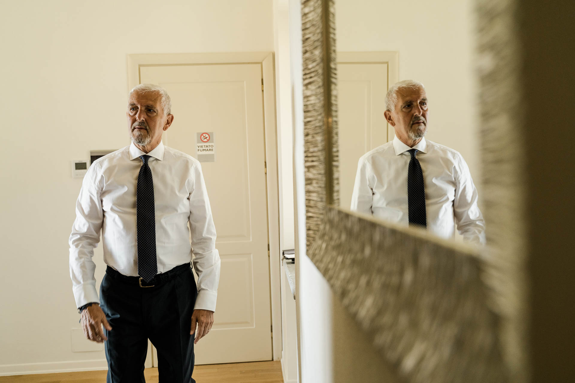 Il papà della sposa si guarda allo specchio, con la cravatta blu