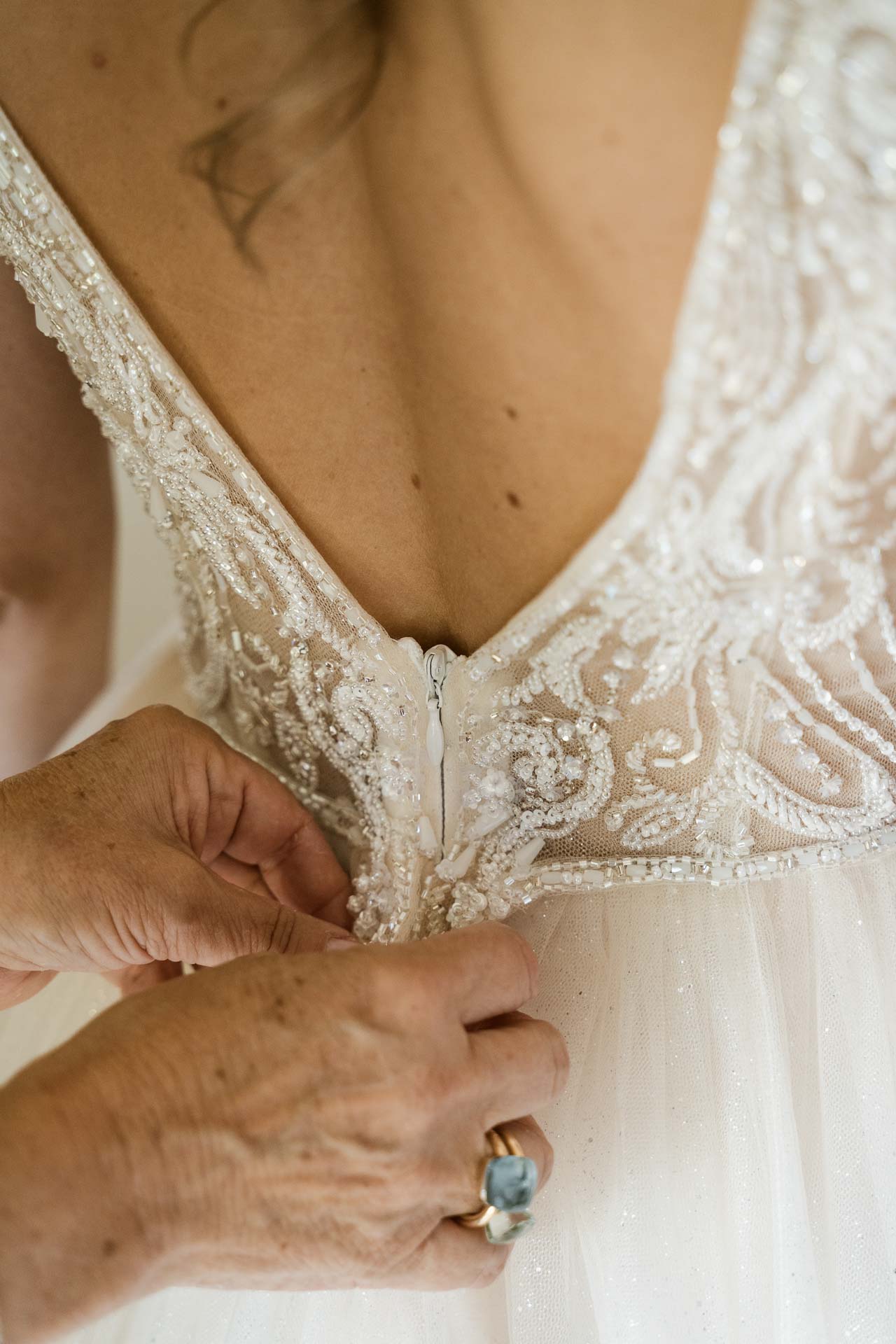 La mamma chiude l'abito ricamato sulla schiena della sposa