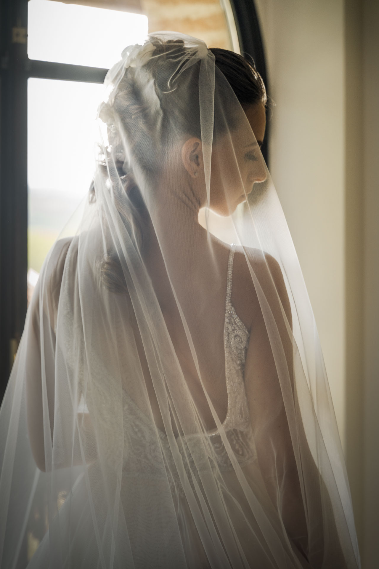 La sposa di spalle sotto il velo, nella luce della finestra